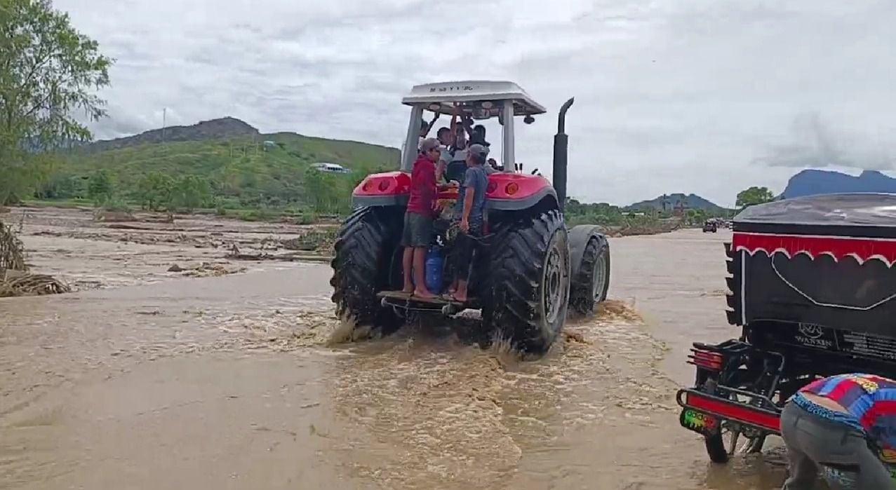 Pobladores cruzan quebradas con ayuda de un tractor.