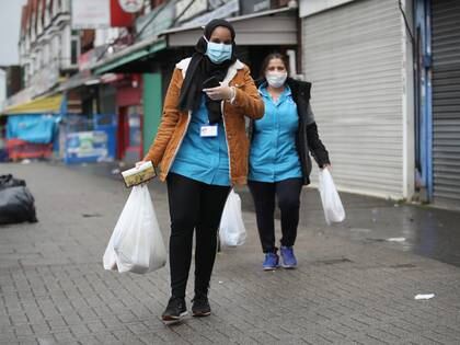 Mujeres caminan por la calle con mascarillas tras hacer las compras en  Sparkhill, Reino Unido
