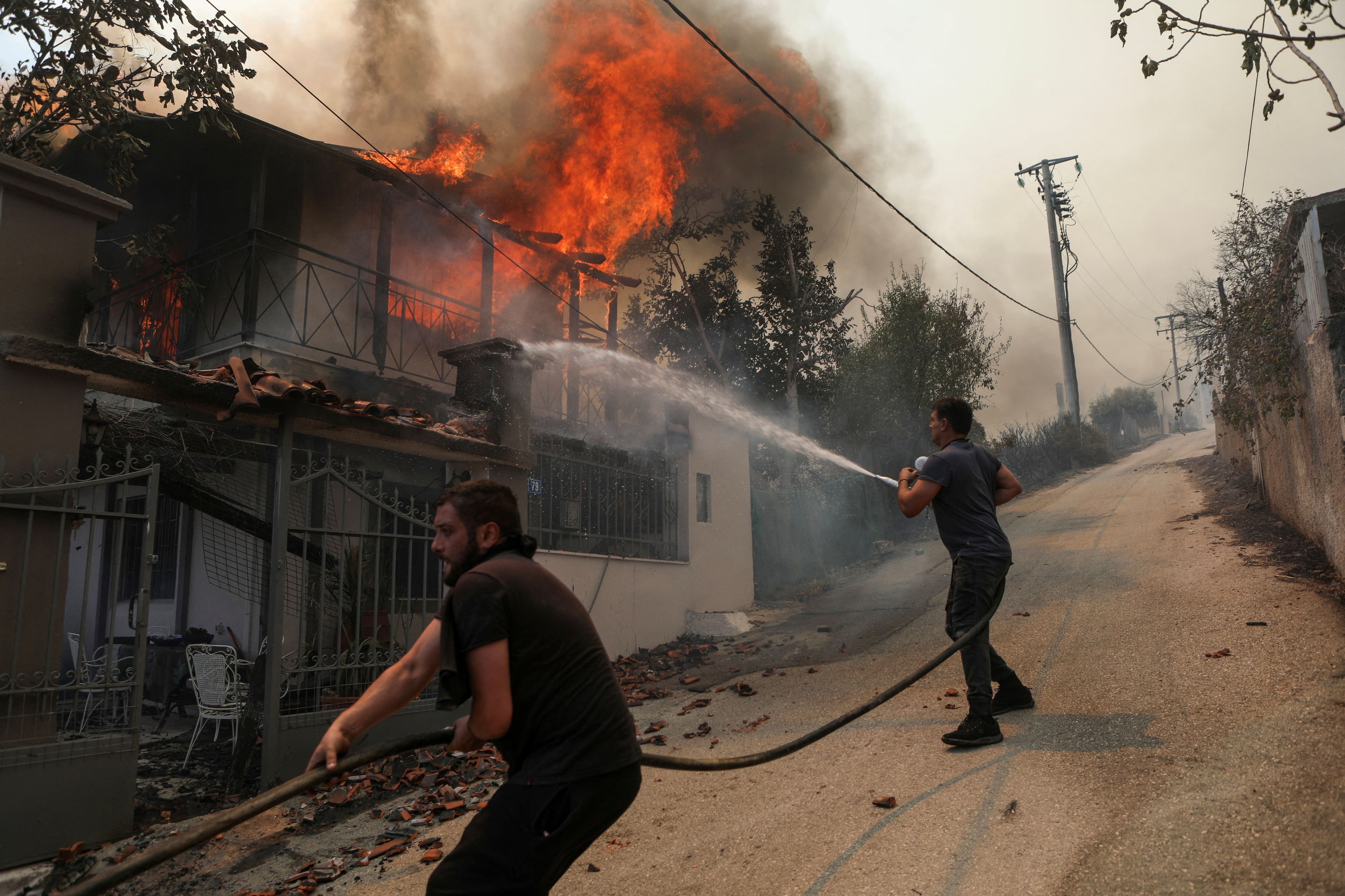 Voluntarios tratan de apagar un incendio en Menidi, cerca de Atenas (Reuters)