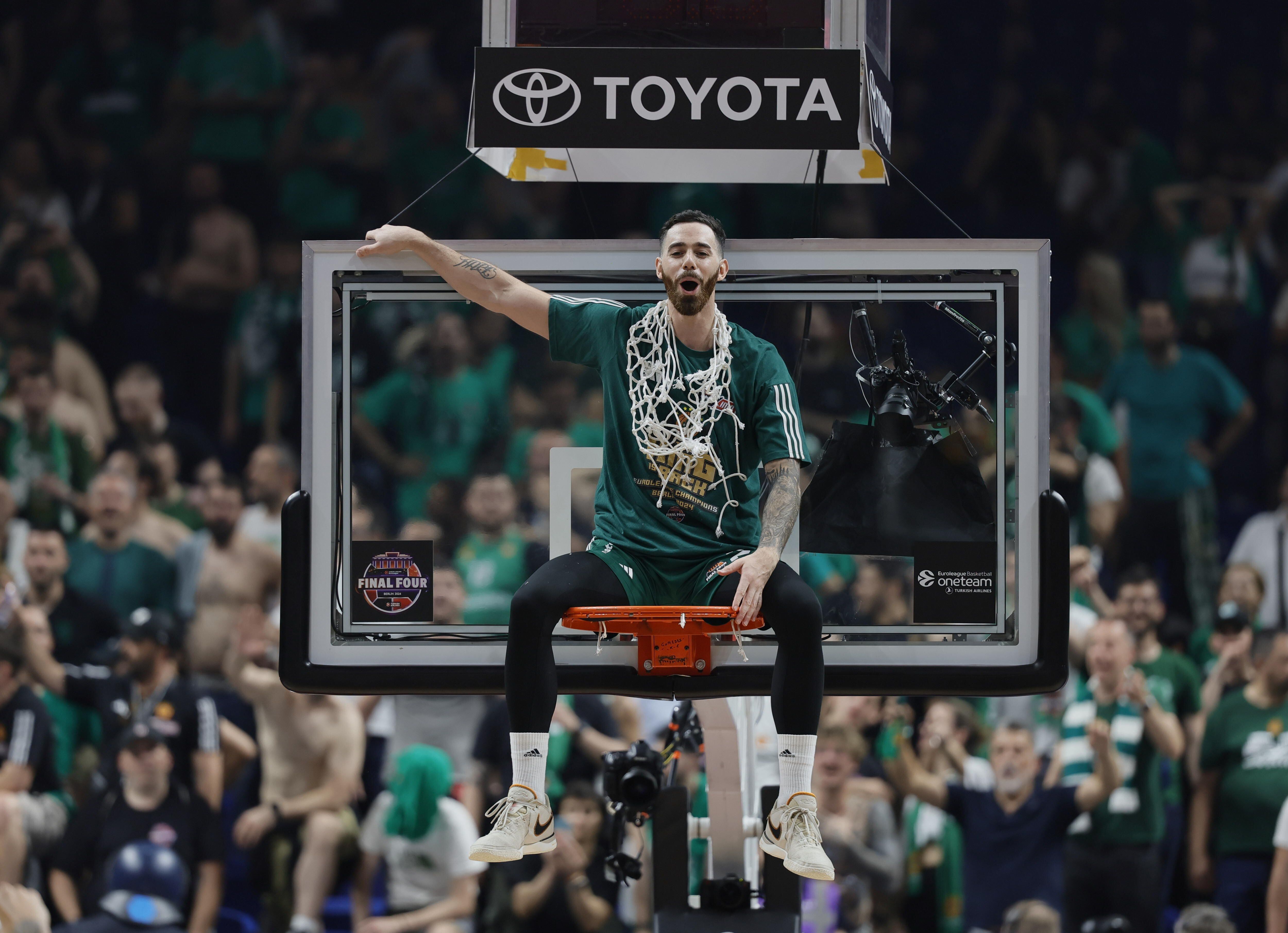 El jugador del Panathinaikos Luca Vildoza celebra la victoria sentado en el aro de una de las canastas del pabellón en Berlín, Alemania (EFE/EPA/RONALD WITTEK) 