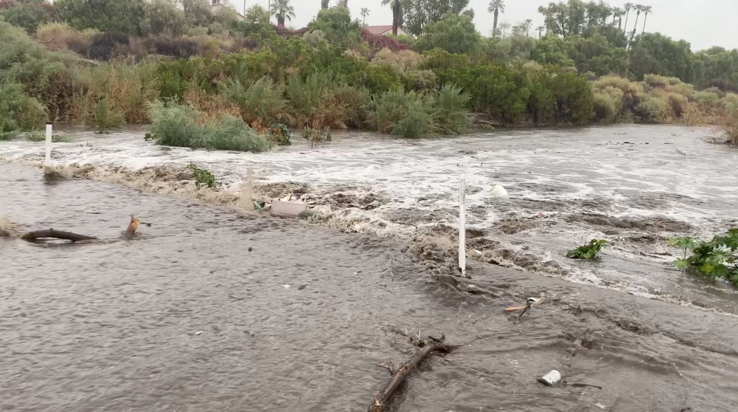 Una vista muestra el agua de la inundación moviéndose a través de la carretera durante la tormenta tropical Hilary, en Palm Springs, California.