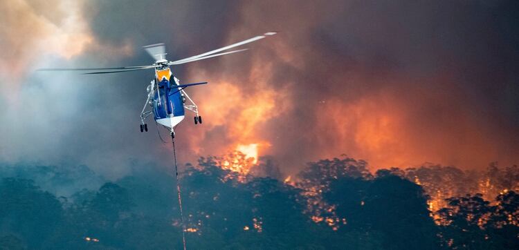 En esta imagen, tomada el 30 de diciembre de 2019 y proporcionada por el gobierno del estado de Victoria, un helicóptero participa en las labores de extinción de un incendio en East Gippsland, Victoria, Australia. (Gobierno estatal de Victoria vía AP)