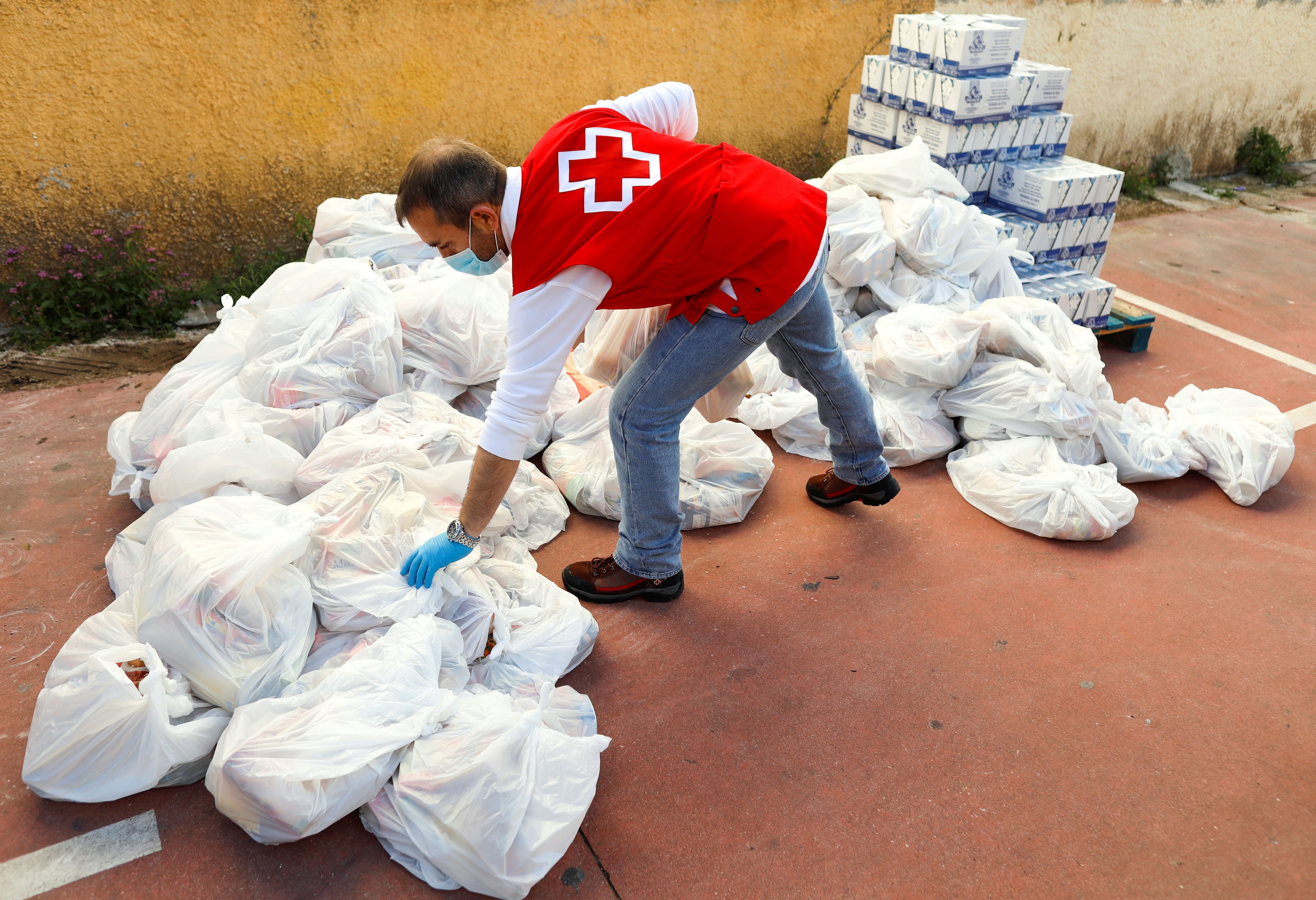 Un miembro de la Cruz Roja Española prepara alimentos para familias necesitadas en un banco de alimentos, como parte de una campaña especial de distribución durante el brote de COVID-19 en Ronda, al sur de España, el 3 de abril de 2020. (REUTERS/Jon Nazca)