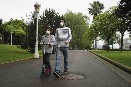 Un niño circula con un patinete junto a un adulto en el primer día en el que los menores de 14 años pueden salir a la calle, en Bilbao. H.Bilbao - Europa Press
