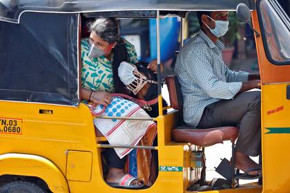 En India, una pasajera, su perro y el conducto deL rickshaw utilizan barbijo