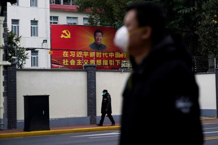 Foto de archivo de personas con mascarillas pasando por una calle junto a un retrato del presidente chino Xi Jinping mientras el país se ve afectado por un brote del nuevo coronavirus en Shanghai. 10 de febrero de 2020. REUTERS/Aly Song