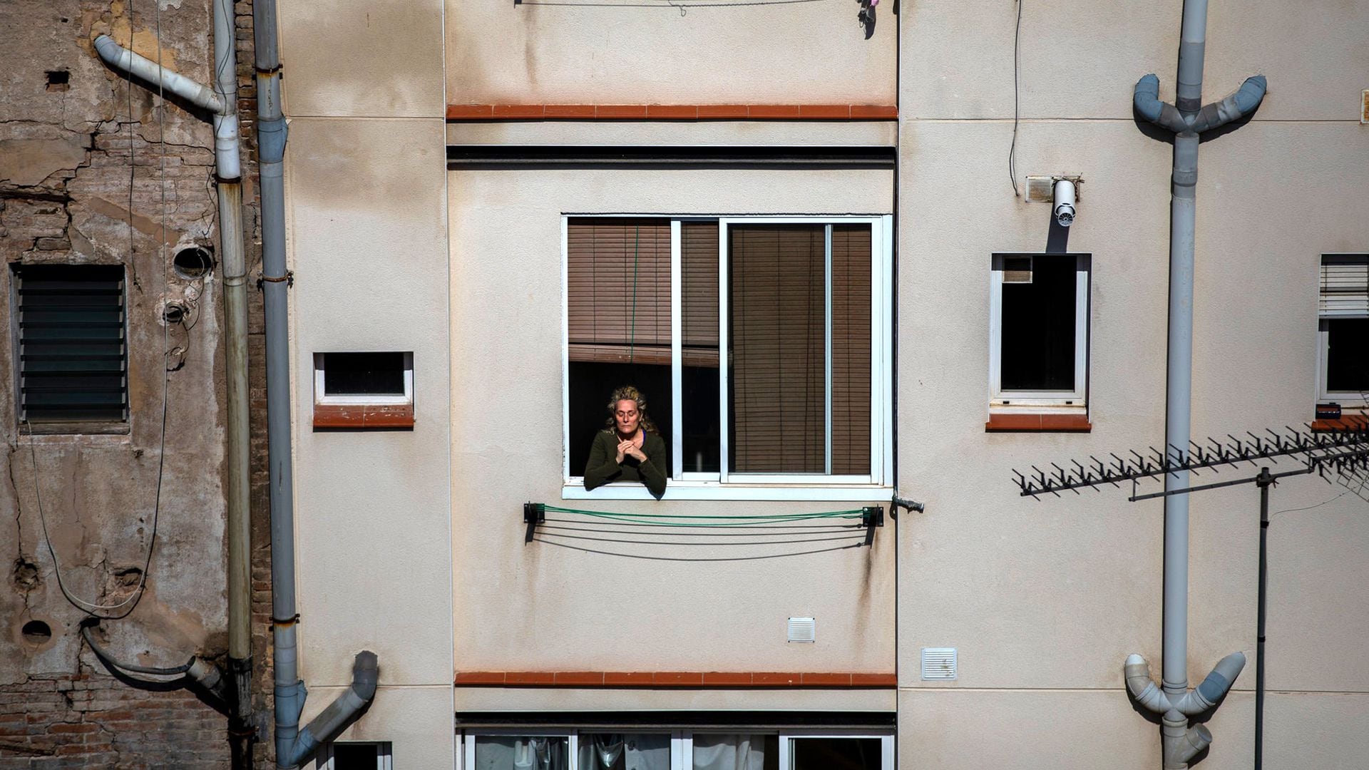 Una mujer se asoma por su ventana durante el confinamiento por el coronavirus, en Barcelona (Foto: Emilio Morenatti/Associated Press)