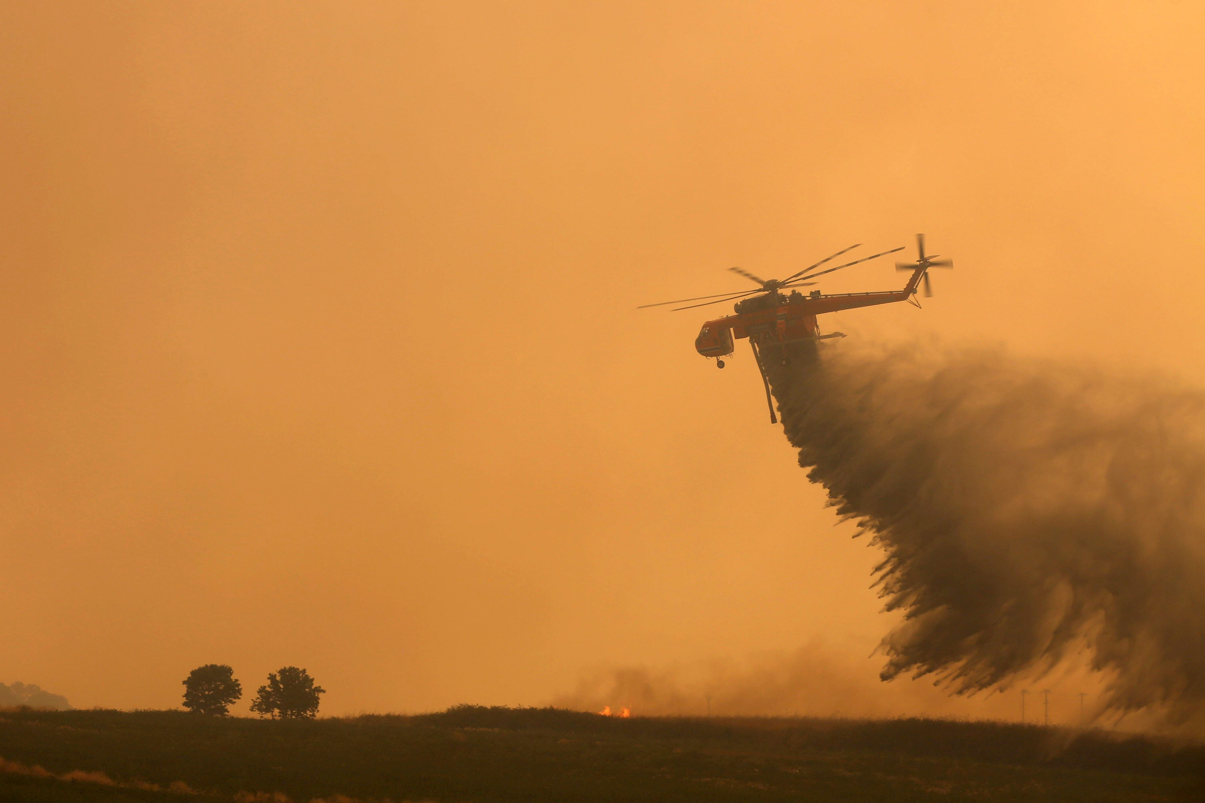 Un helicóptero de extinción de incendios arroja agua para extinguir la zona industrial de Alexandroupolis, Tracia, al norte de Grecia. EFE/EPA/DIMITRIS ALEXOUDIS/Archivo