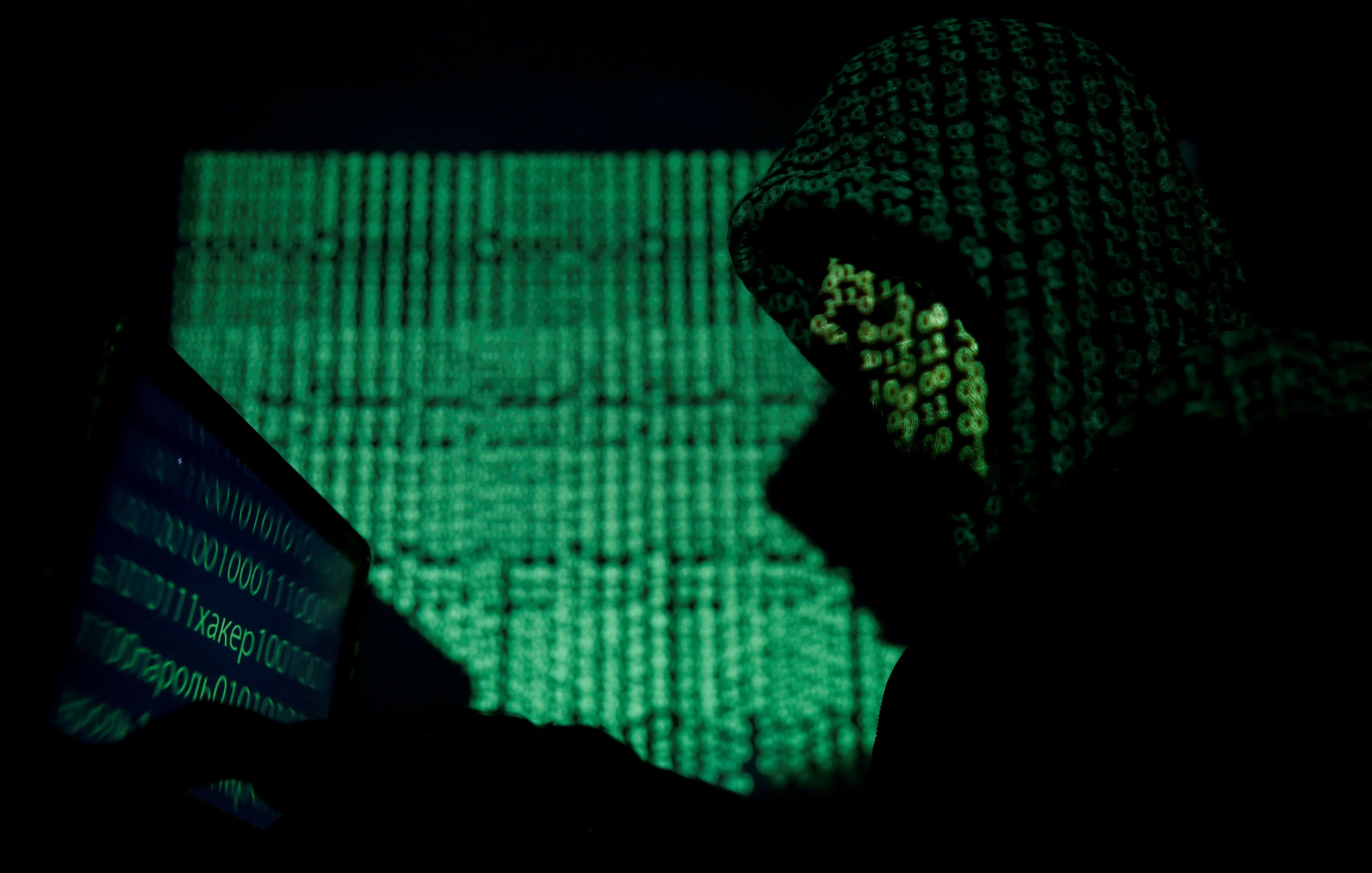 FOTO DE ARCHIVO: Un hombre encapuchado sostiene una computadora portátil mientras se proyecta un código cibernético sobre él en esta fotografía ilustrativa tomada el 13 de mayo de 2017. REUTERS/Kacper Pempel/Illustration/File Photo