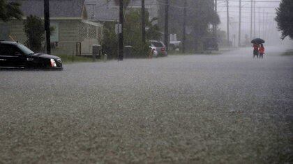 Una coppia in alto attraverso l'acqua alta sulla 59th Street vicino a Avenue S a Galveston, Texas, mercoledì, settembre. 18, 2019, come pioggia pesante dalla depressione tropicale Imelda ha causato inondazioni di strada sull'isola. (Jennifer Reynolds / The Galveston County County Notizie quotidiane Via AP)