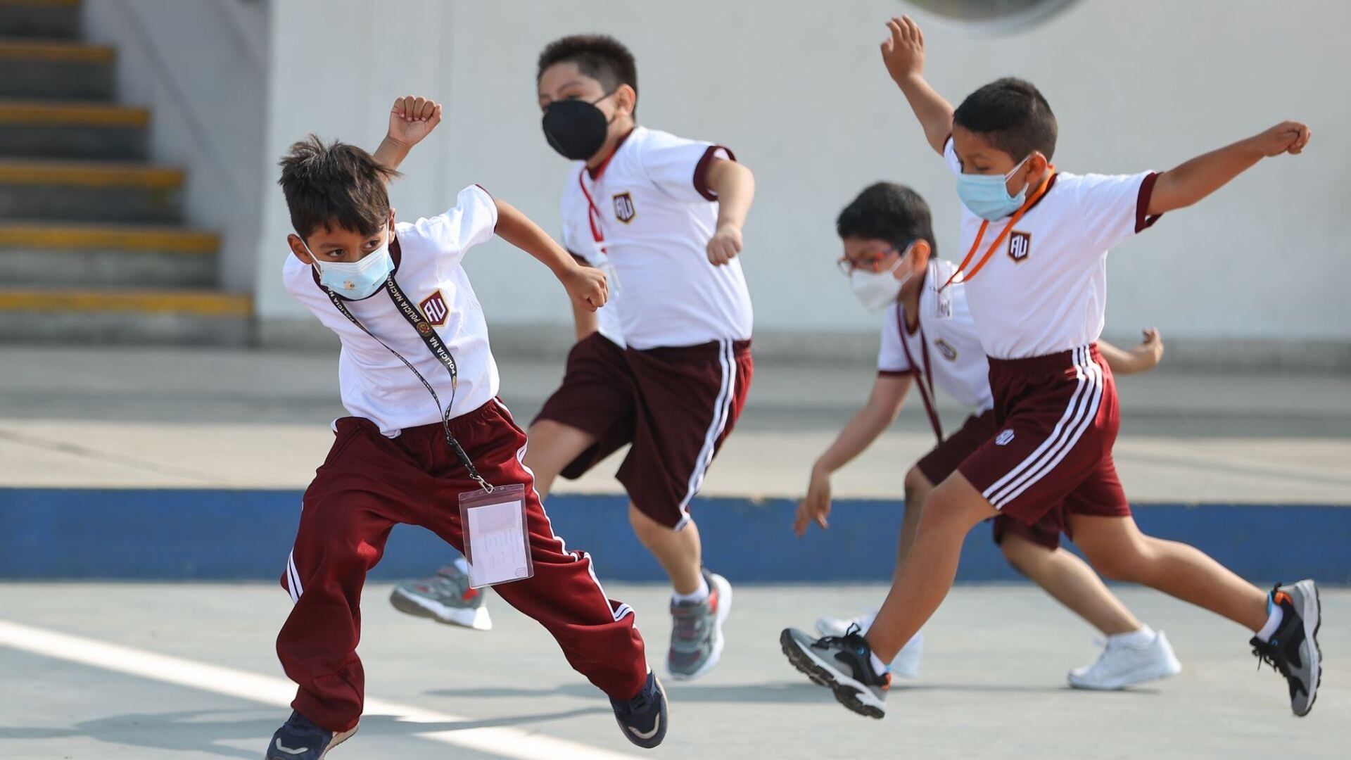 Un grupo de niños del nivel primaria corriendo en el patio de un colegio de Lima - Perú.