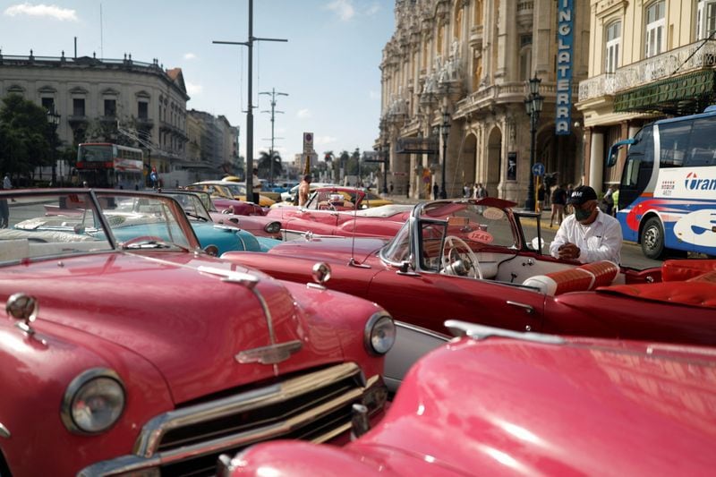 Motoristas de táxi e veículos antigos esperam por turistas em Havana, Cuba.