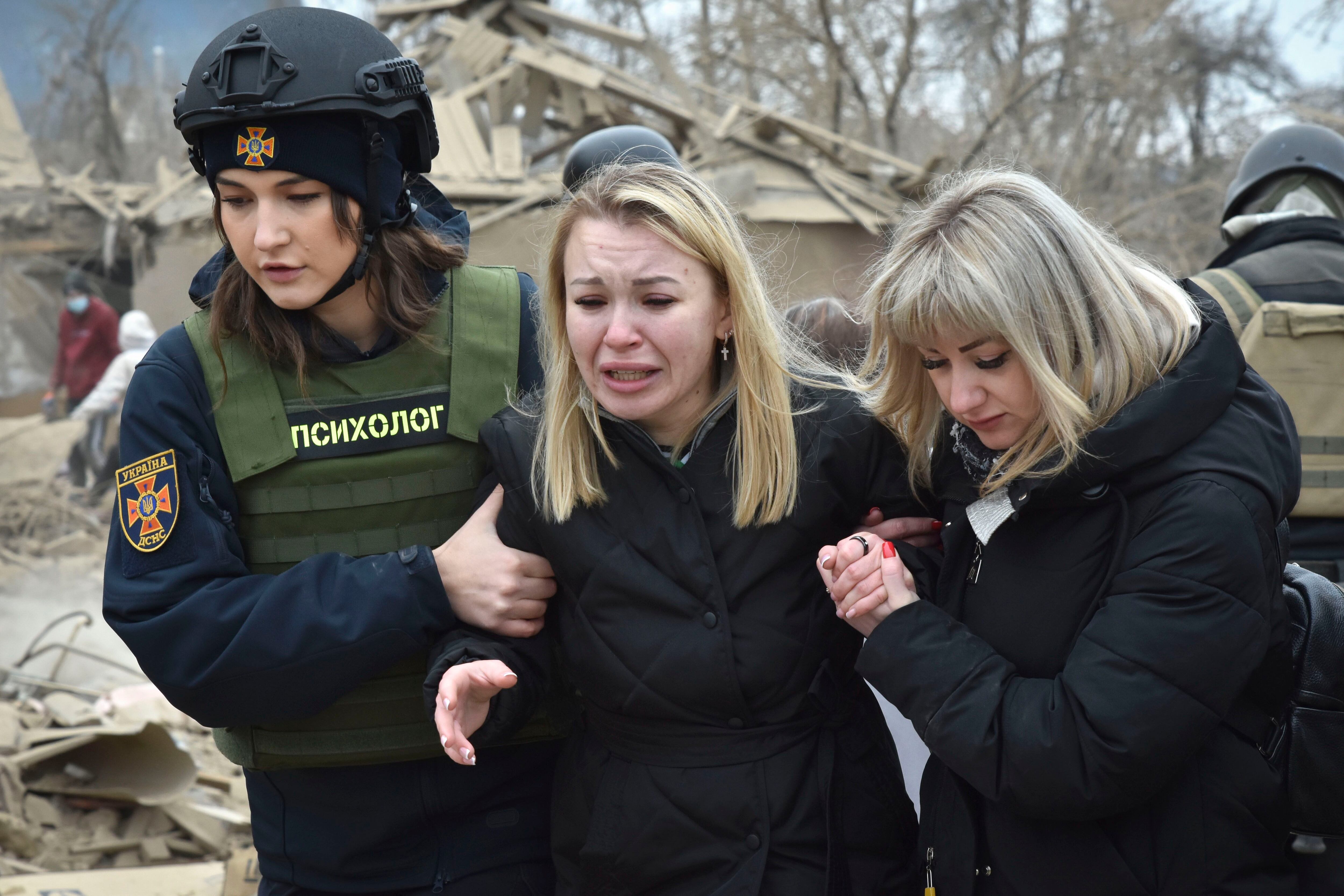 Una psicóloga de los servicios de emergencias (izquierda), consuela a una mujer en el escenario de un ataque aéreo ruso (AP Foto/Andriy Andriyenko)