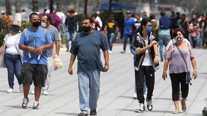 Los turistas caminan por el paseo marítimo de la Laguna de Chapala en Chapala, estado de Jalisco, México, después de la flexibilización de las medidas y restricciones impuestas para combatir la propagación del nuevo coronavirus, COVID-19, el 12 de julio de 2020. (Foto por Ulises RUIZ / AFP)