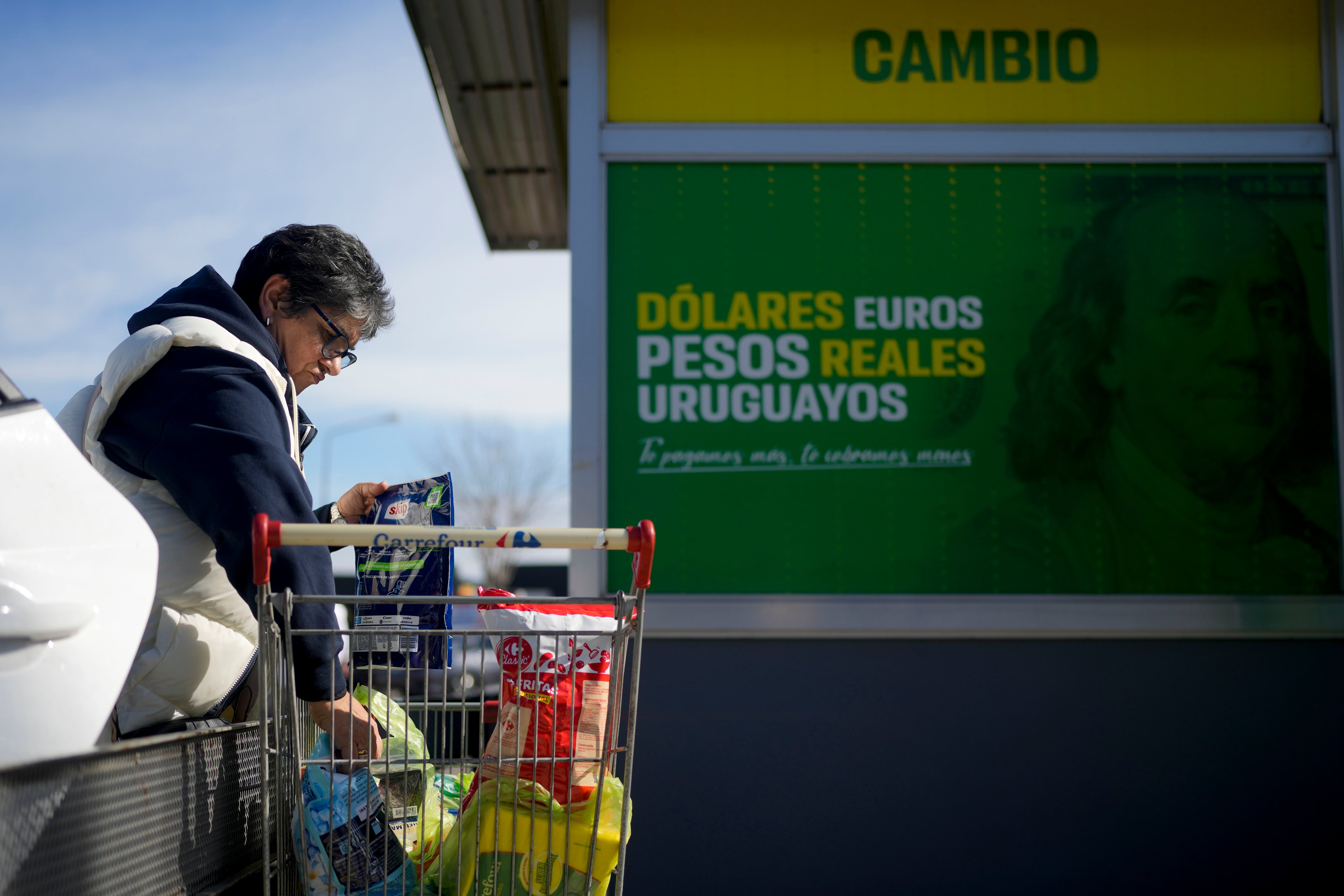 La uruguaya Consuelo Ramírez, trabajadora social, descarga su carrito de compras frente a un supermercado donde está abierta una casa de cambio de divisas en Gualeguaychú, en la provincia de Entre Ríos, Argentina, a pocos kilómetros de la frontera con Uruguay, el viernes 30 de junio de 2023. Los uruguayos compran dólares estadounidenses en Uruguay, luego cruzan la frontera con esos dólares hacia Argentina, donde los usan para comprar pesos argentinos en el mercado negro a casi el doble del tipo de cambio oficial. (Foto AP/Natacha Pisarenko)