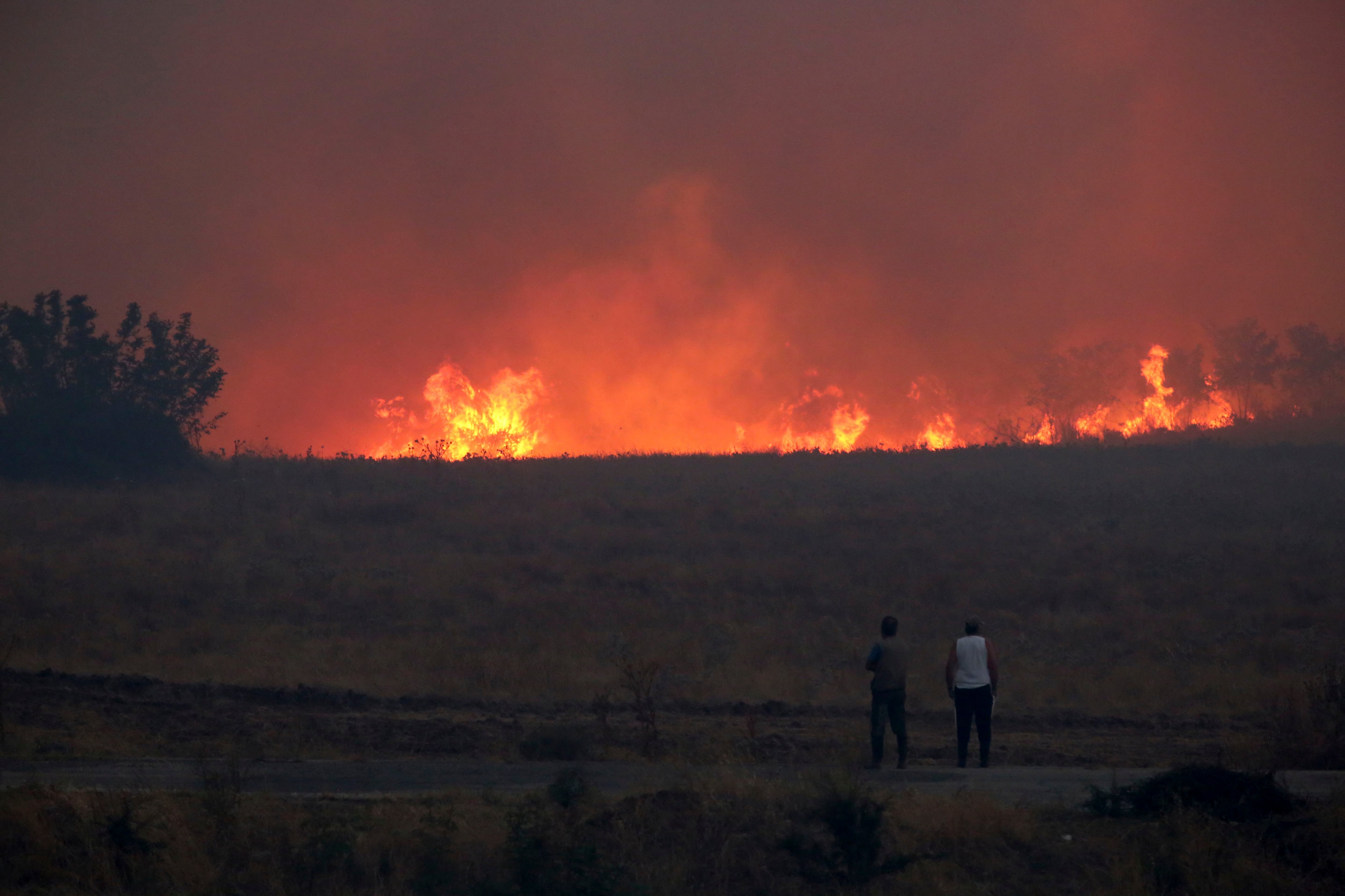 Gente observa un incendio forestal cerca de la ciudad nororiental de Alejandrópolis, Grecia, el domingo 20 de agosto de 2023. (Ilias Kotsireas/InTime News vía AP)