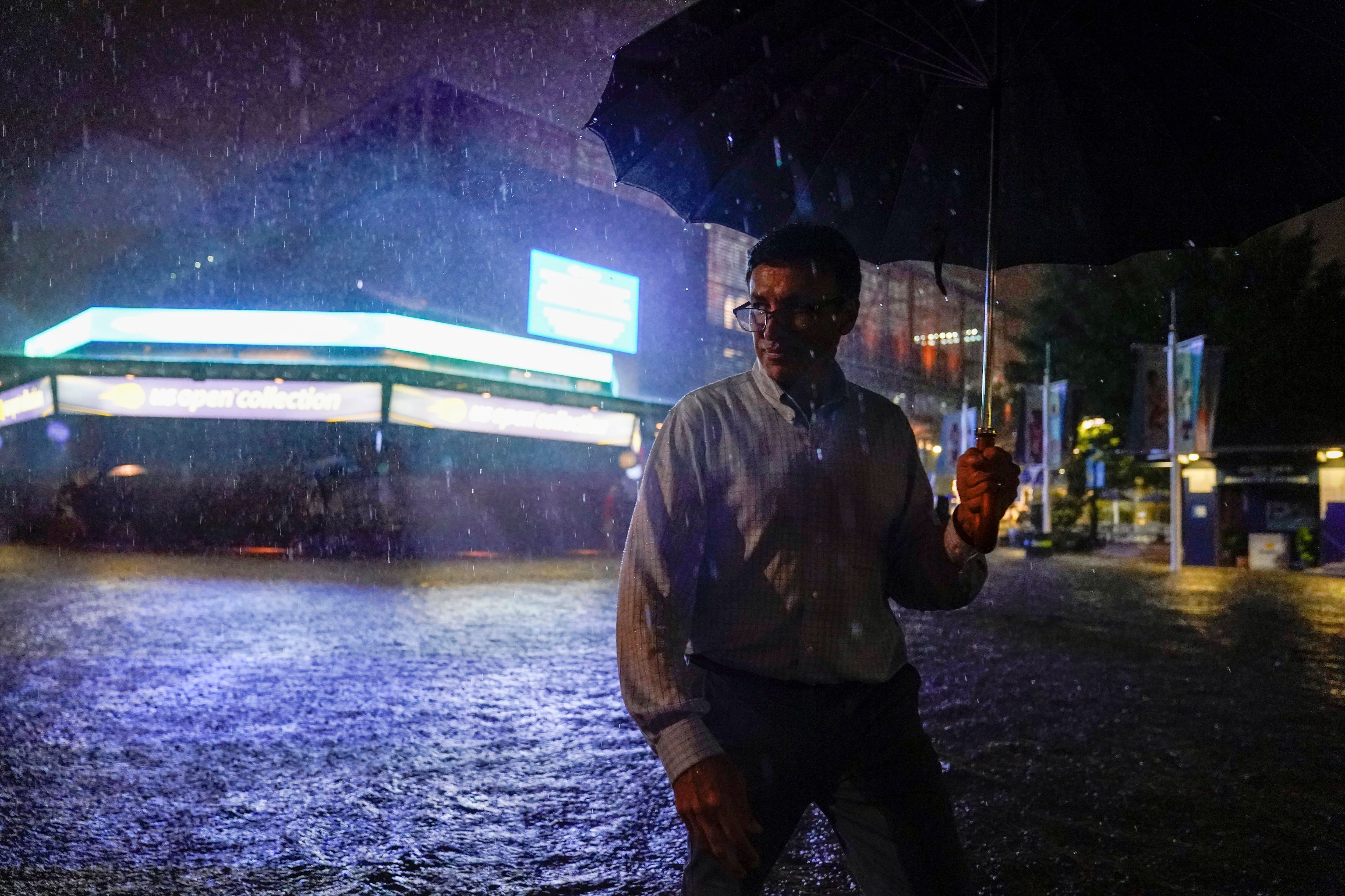 Un espectador camina por el pabellón inundado frente al estadio Louis Armstrong en el tercer día del torneo de tenis US Open 2021. (Danielle Parhizkaran-USA TODAY a través de REUTERS)