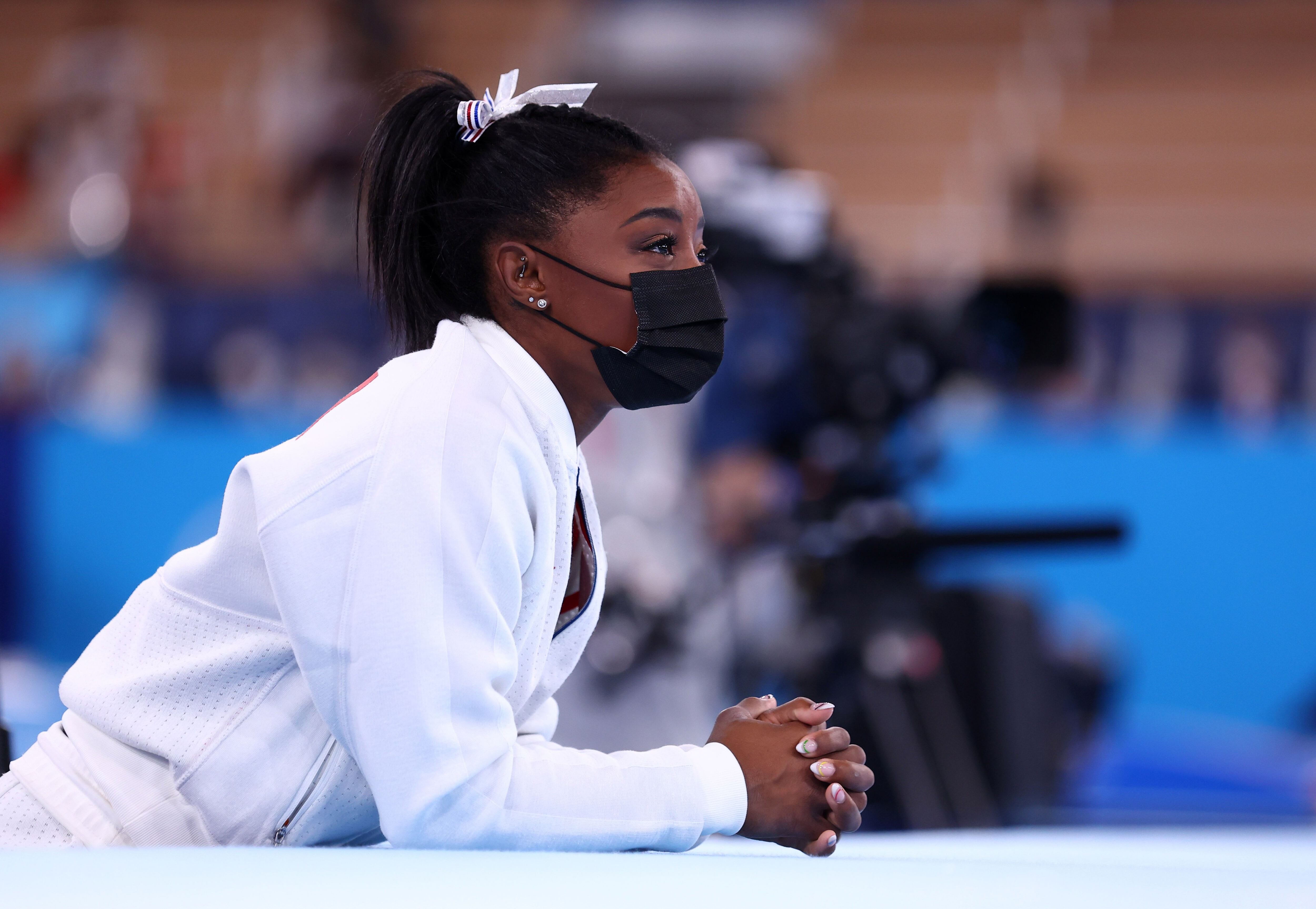  Simone Biles de los Estados Unidos con una máscara observa a sus compañeros de equipo