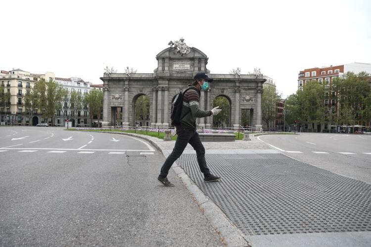 Un hombre con una máscara protectora y guantes pasa por la Puerta de Alcalá, en medio del brote de la enfermedad coronavirus (COVID-19) en Madrid, España, el 9 de abril de 2020. REUTERS/Sergio Pérez