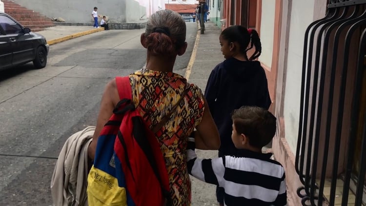 Una abuela camina por las calles de Caracas tras recoger en la escuela a sus nietos que quedaron a su cuidado tras el exilio de sus padres