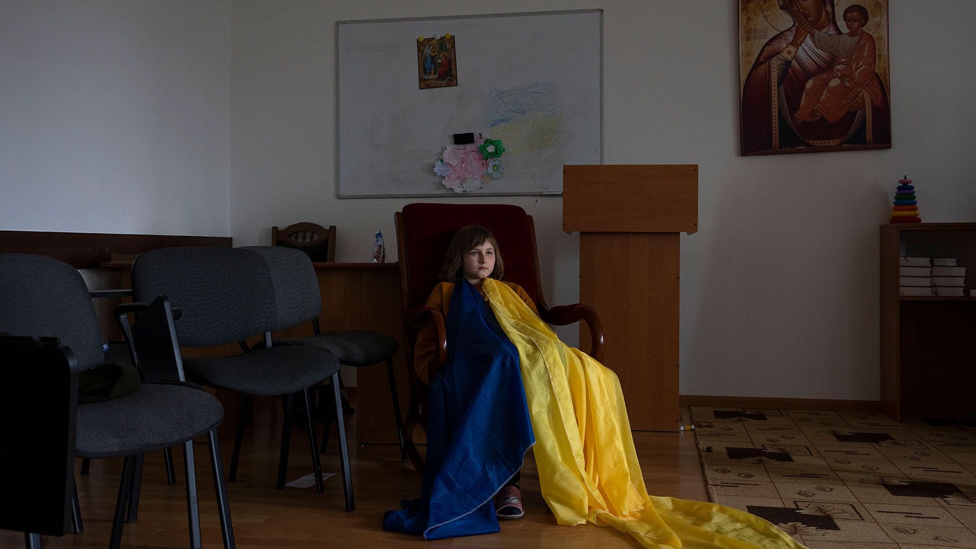 Una niña desplazada internamente, con una bandera ucraniana improvisada, se sienta durante una clase de actividades con monjas, mientras se refugia en el Monasterio de Mujeres Hoshiv, en la región de Ivano-Frankivsk, en el oeste de Ucrania, el miércoles 6 de abril de 2022.
 (Foto AP/Nariman El-Mofty)
