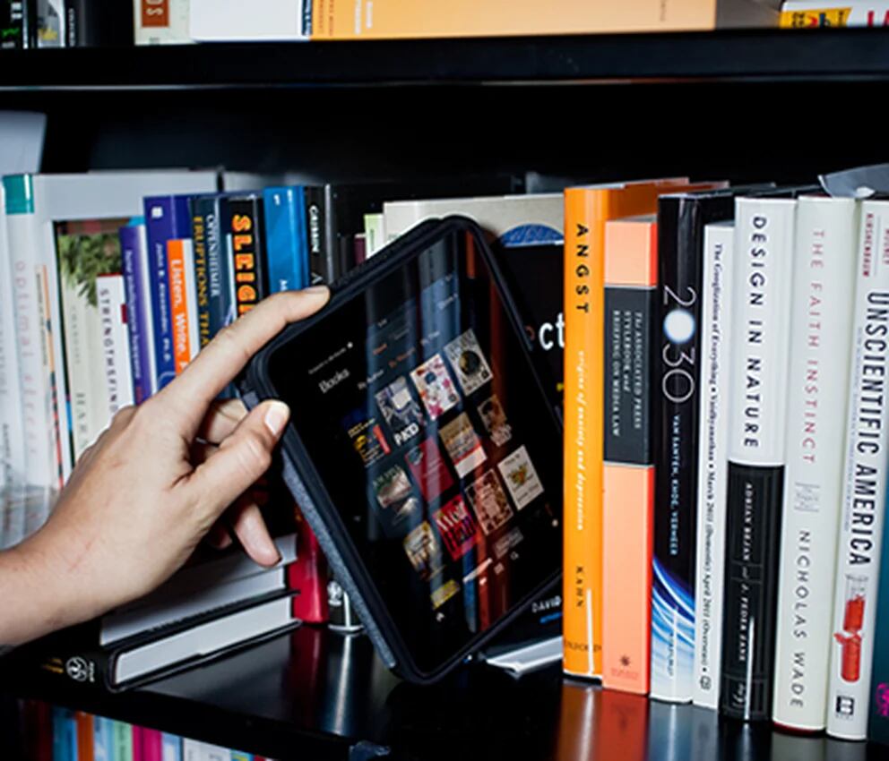 Un  Kindle lector de ebooks en una estantería con libros en