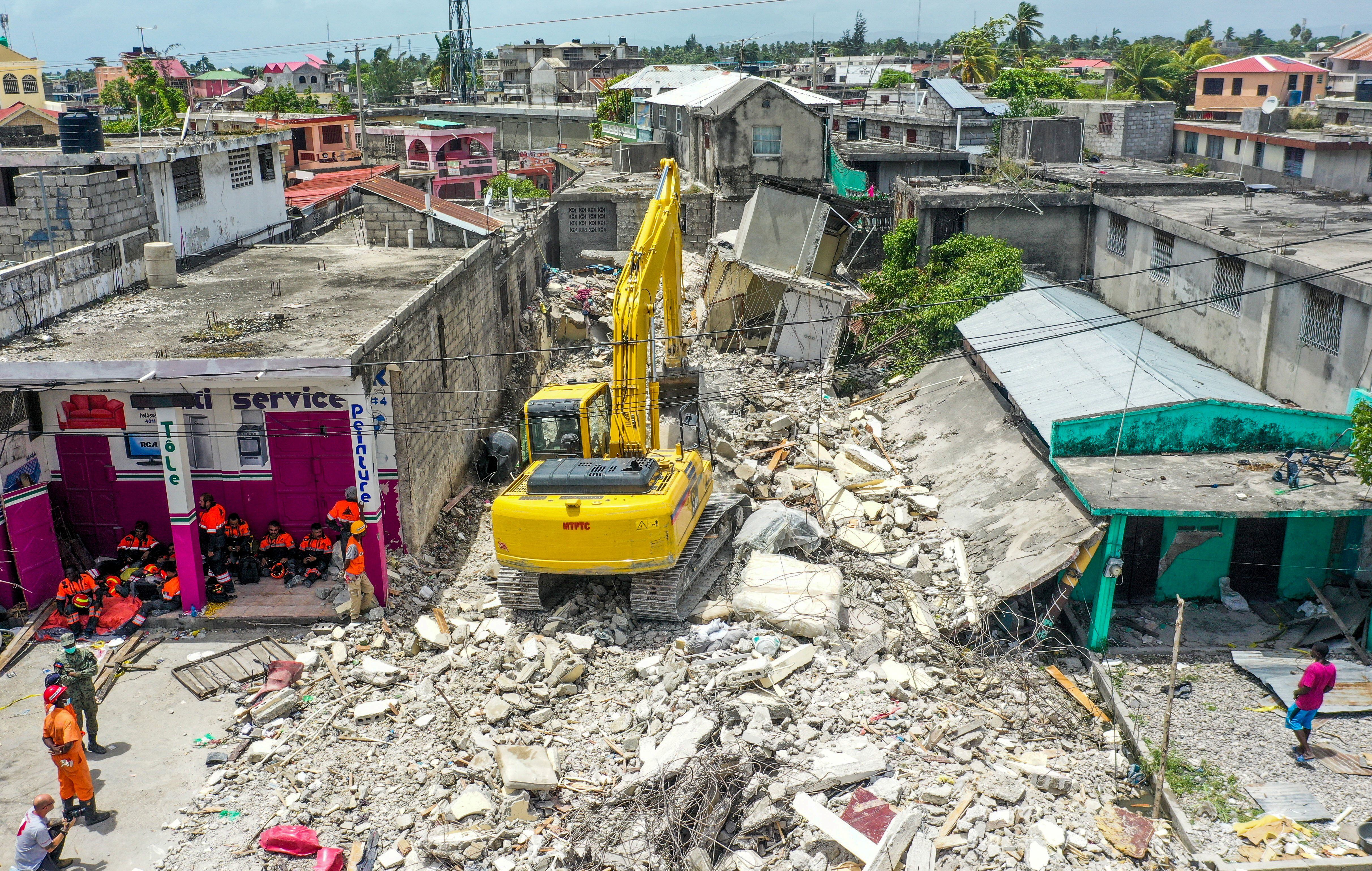 Miembros del equipo de rescate mexicano, conocido como "Topos", se toman un descanso mientras una retroexcavadora retira los escombros de una casa derrumbada una semana después de que un terremoto azotara la región, matando a más de 2.200 personas y destruyendo decenas de miles de edificios, en Les Cayes, Haití.  REUTERS / Ralph Tedy Erol 