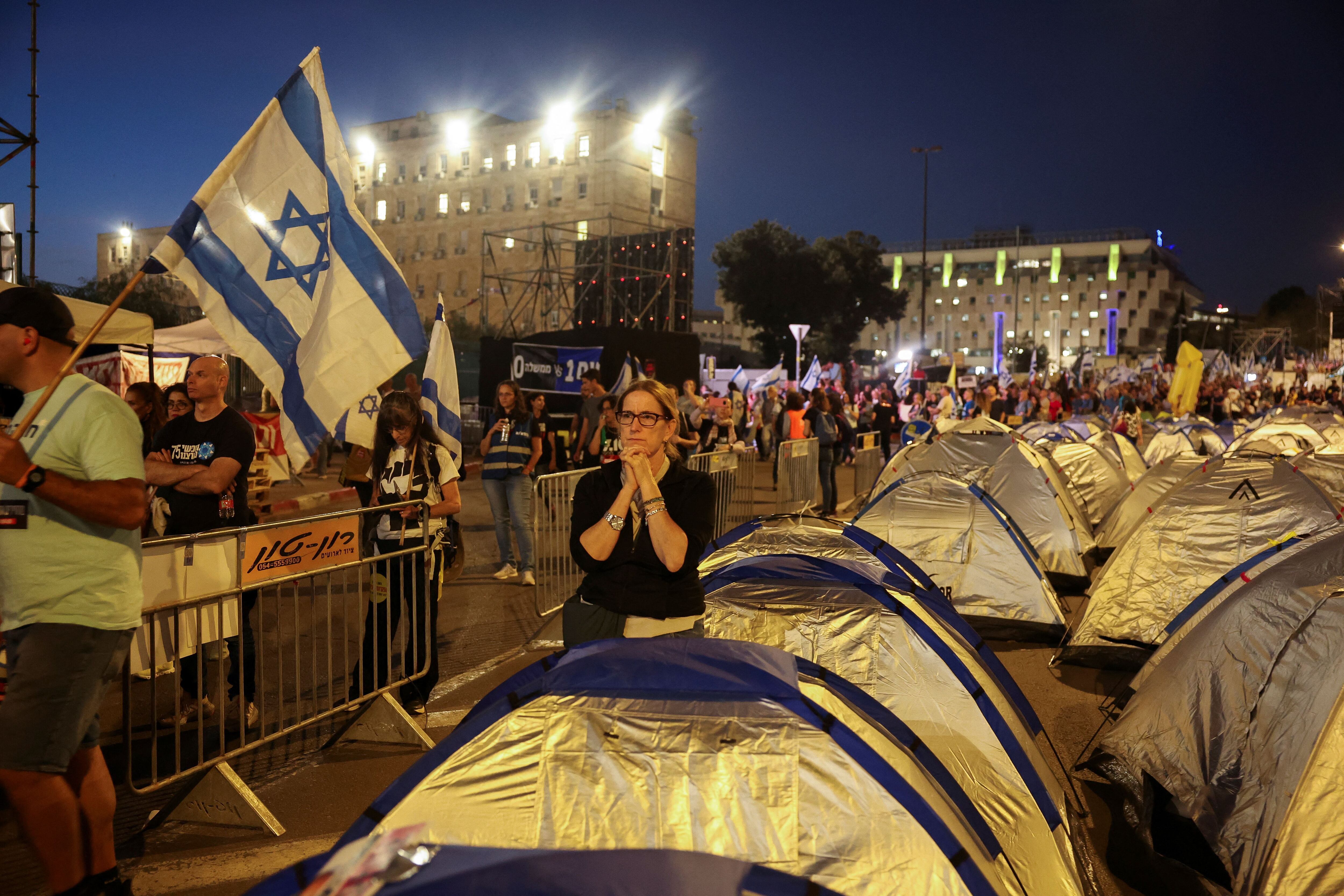 Una mujer se encuentra junto a tiendas de campaña, mientras los manifestantes exigen el derrocamiento del primer ministro israelí, Benjamin Netanyahu, tras el mortal ataque del 7 de octubre contra Israel por parte del grupo islamista palestino Hamás y la consiguiente guerra en Gaza, en una manifestación en Jerusalén, el 1 de abril. 2024. REUTERS/Ronen Zvulun