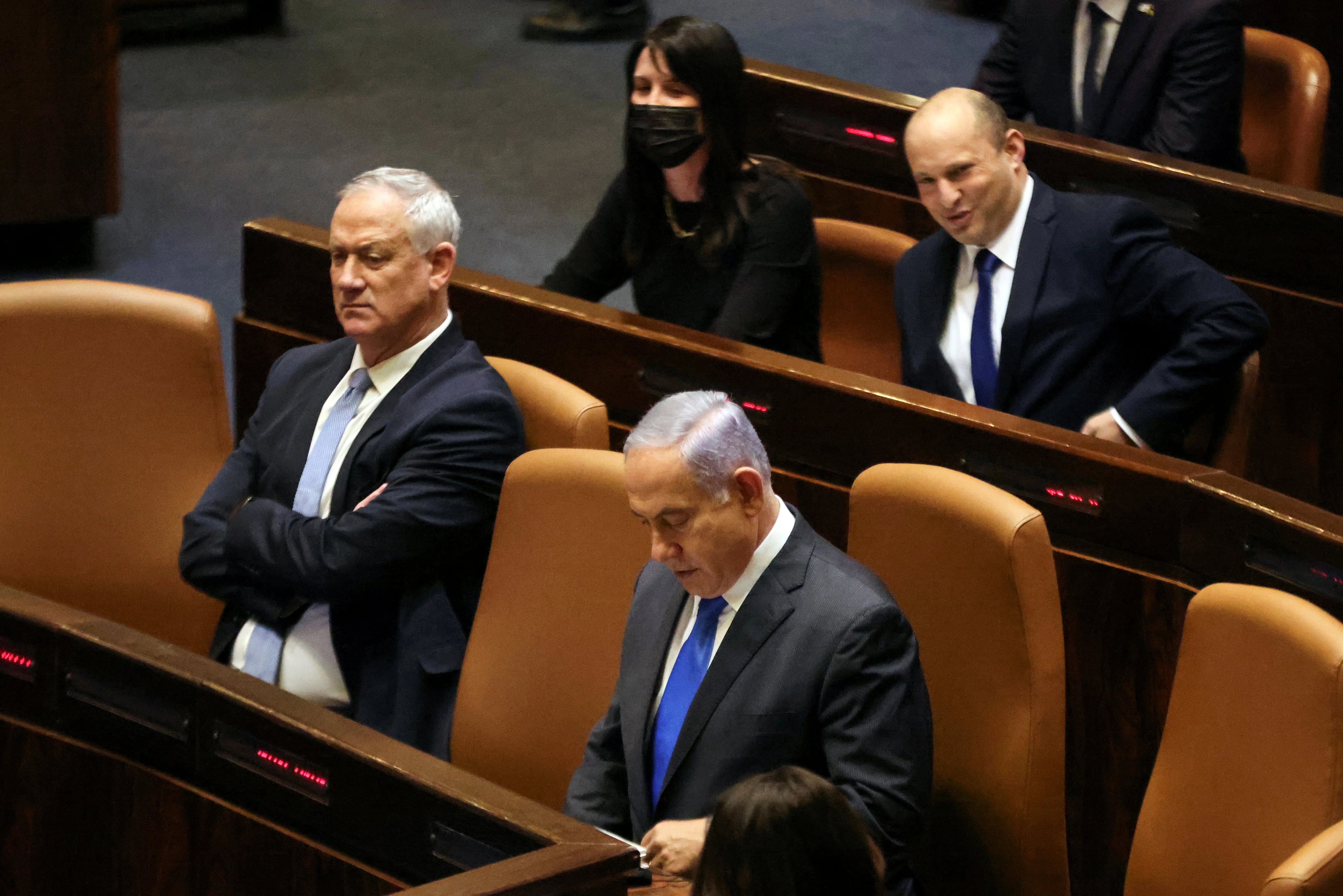 Naftali Bennett, Prime Minister-designate, Israeli Prime Minister Benjamin Netanyahu and Blue and White party leader Benny Gantz, sit nearby during a special session of the Knesset, Israel's parliament, to approve and swear-in a new coalition government, in Jerusalem June 13, 2021. REUTERS/Ronen Zvulun