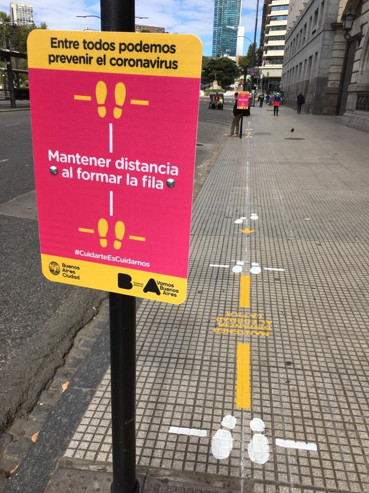 Los pies dibujados sobre la vereda ayudan a los viajeros a mantener la distancia mínima de un metro y medio para reducir así la posibilidad de contagio de coronavirus