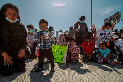 Un grupo de personas migrantes, rezan hoy miércoles, en las inmediaciones del puerto fronterizo del Chaparral ciudad fronteriza de Tijuana.  EFE/Joebeth Terríquez
