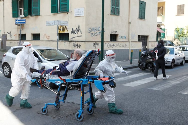 Personal médico vistiendo equipo de protección trasladan a un paciente en una camilla en Italia, en medio de la propagación de la enfermedad por coronavirus (REUTERS)