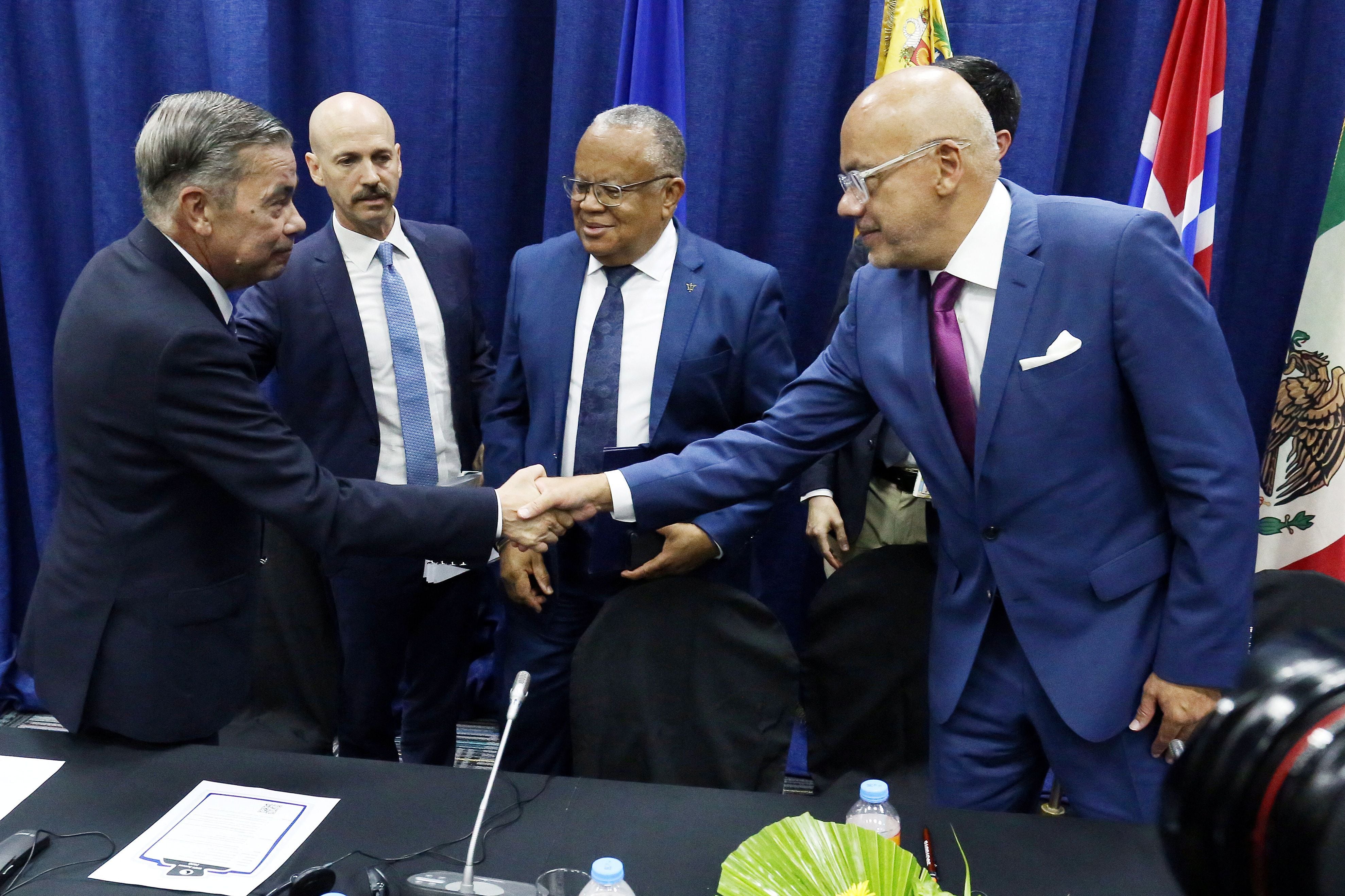 Gerardo Blyde le da la mano a Jorge Rodriguez en Barbados (REUTERS/Nigel R. Browne/Nu-Image Digital Media)