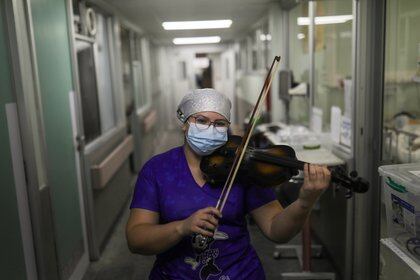 La enfermera chilena Damaris Silva toca el violín para los pacientes que coronavirus en la Unidad de Cuidados Intensivos (UCI) del hospital El Pino de San Bernardo, en Santiago de Chile, el 2 de julio de 2020 (REUTERS/Pablo Sanhueza)