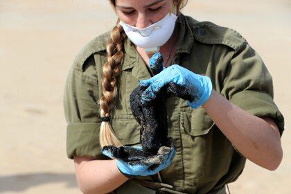 Una soldado israelí trabaja en la descontaminación de una playa (REUTERS / Ronen Zvulun)