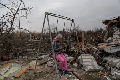 Una niña utiliza su teléfono móvil mientras está sentada en un columpio en un complejo de casas residenciales fuertemente dañadas durante un ataque de drones rusos en Odesa  (REUTERS/Serhii Smolientsev)