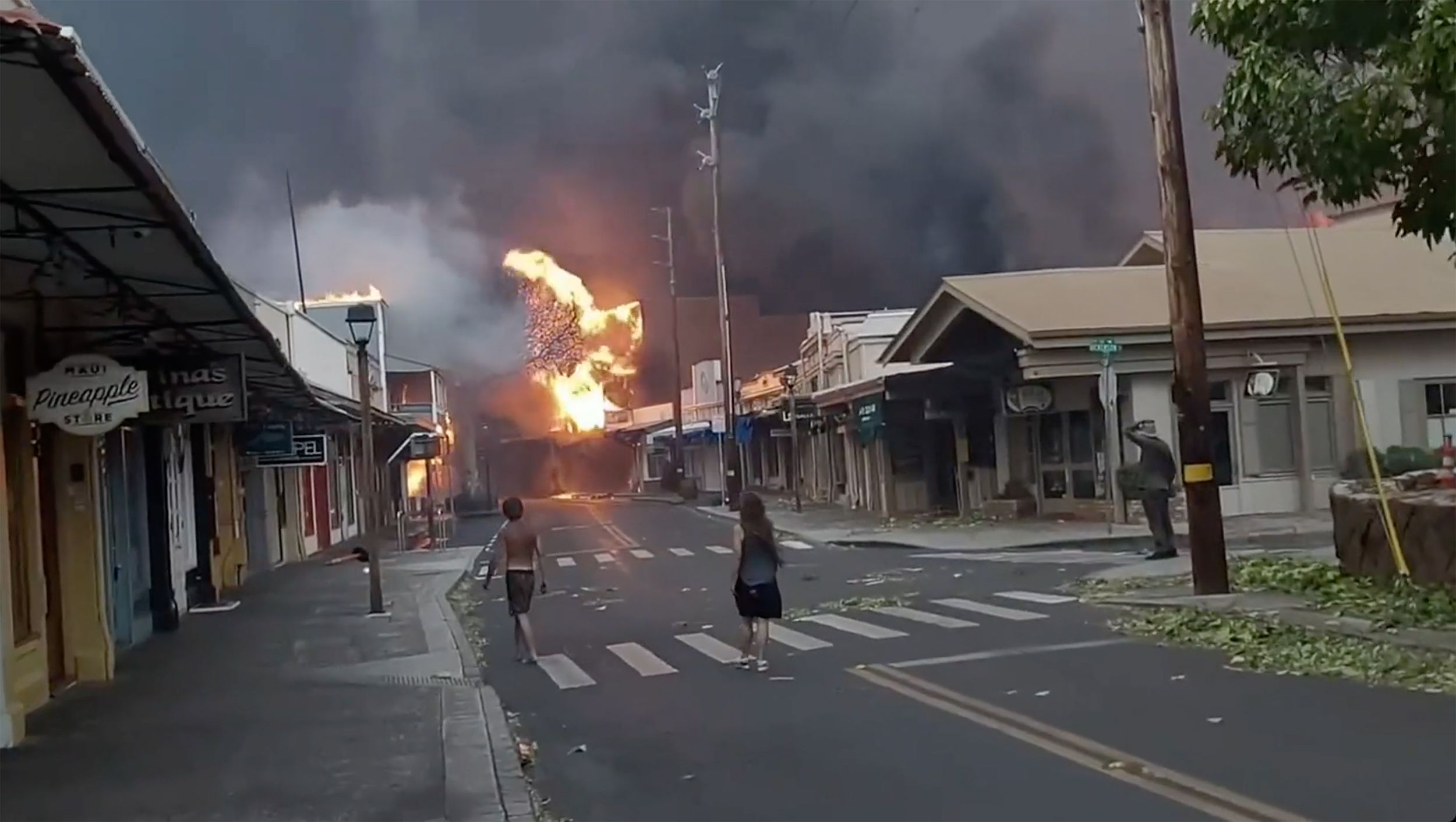 En la calle Front, en el centro de Lahaina, la gente observa cómo el humo y las llamas llenan el aire debido a los voraces incendios forestales. (Alan Dickar via AP)