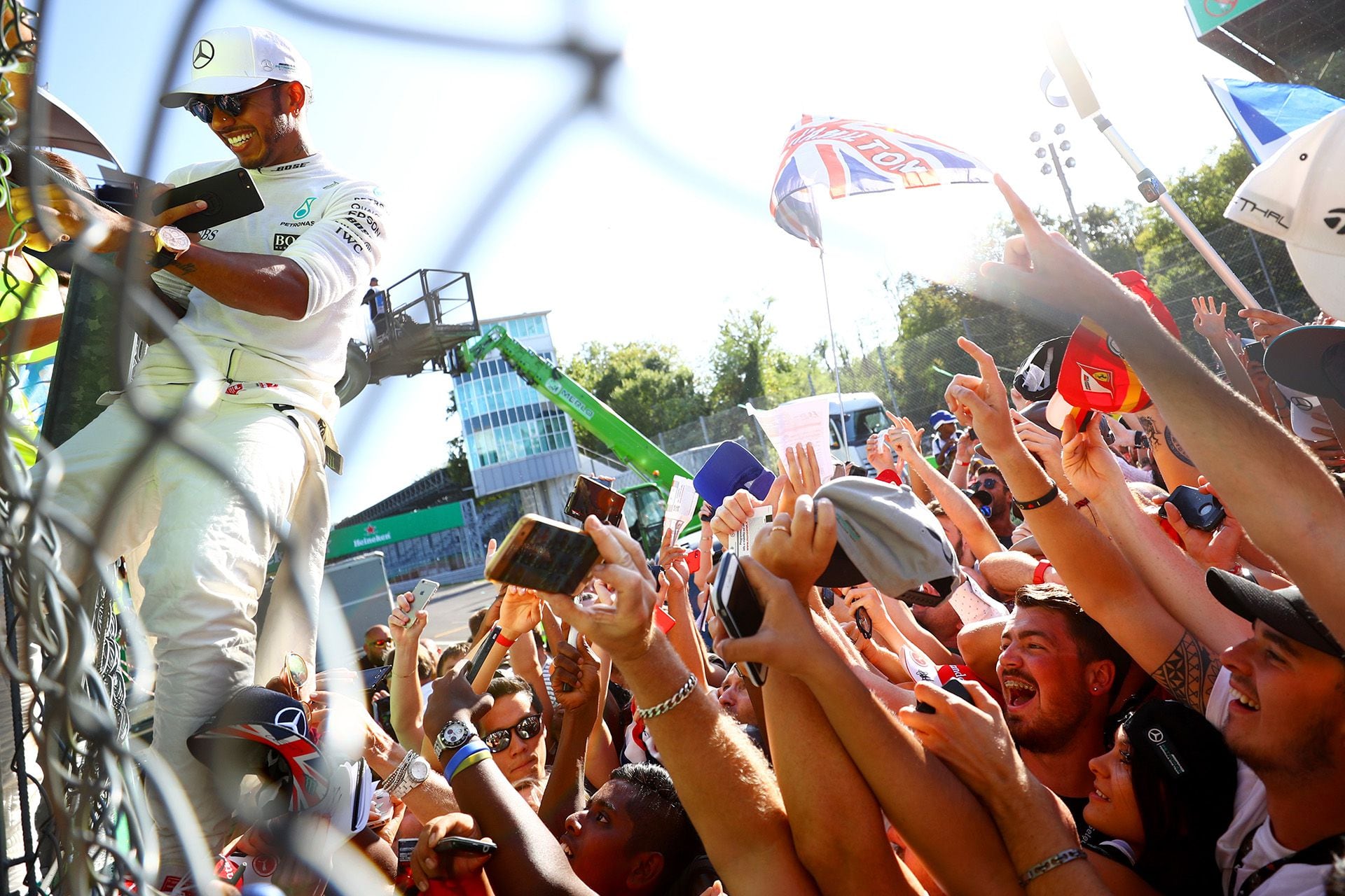 Lewis Hamilton trepando el alambrado de los boxes de Monza para llegar al podio y detrás una multitud. En su momento no fue querido por ganarle siempre a Ferrari, pero por su actitud dentro y fuera de la pista se convertirá en ídolo de los tifosis (Photo by Dan Istitene/Getty Images)