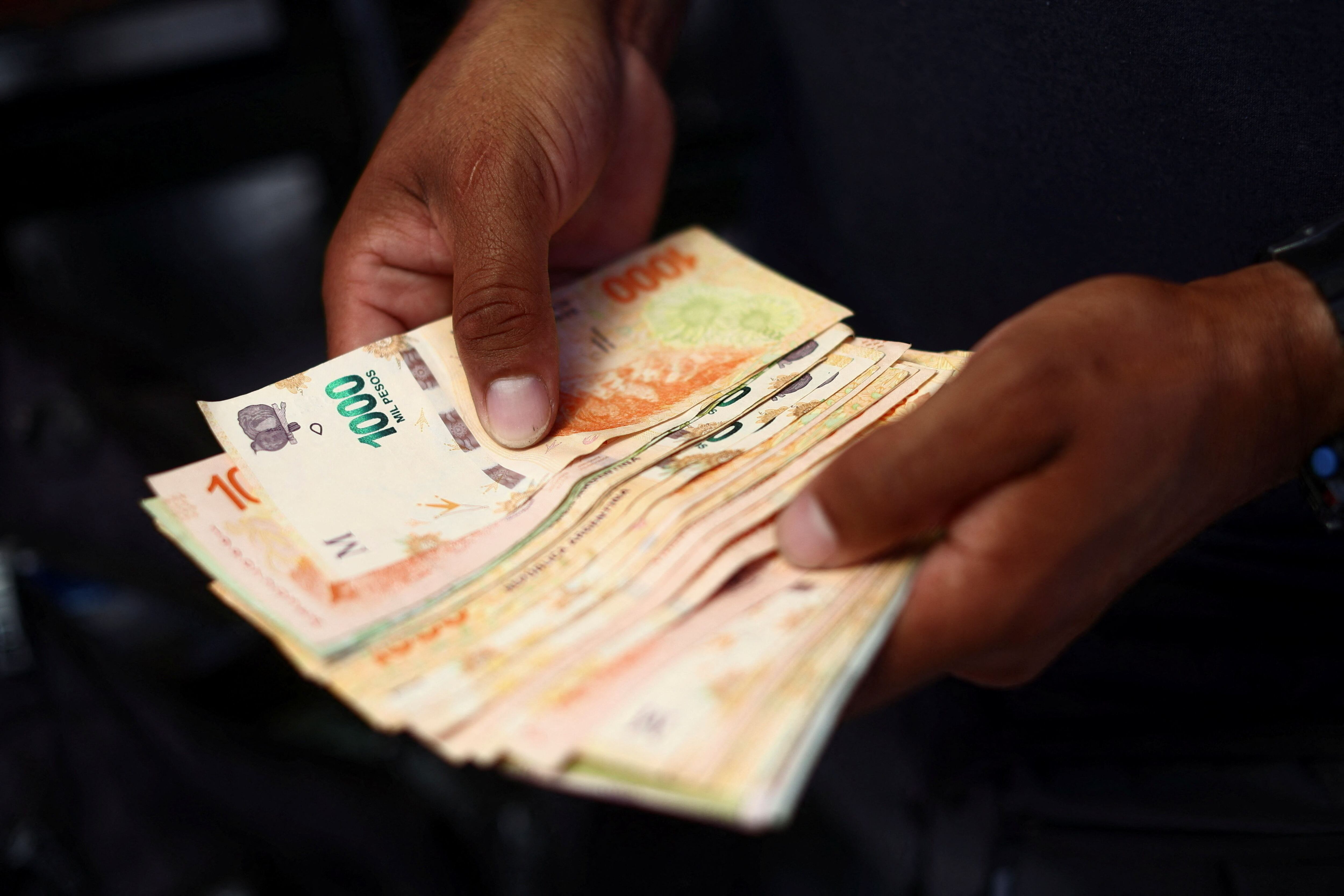 A street food vendor counts money in Buenos Aires, Argentina, December 12, 2023. REUTERS/Tomas Cuesta