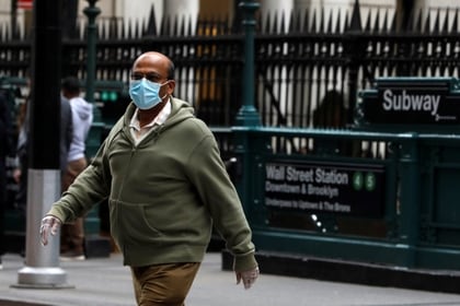 Un hombre con mascarilla y guantes camina cerca a la estación Wall Street en Nueva York (Reuters)