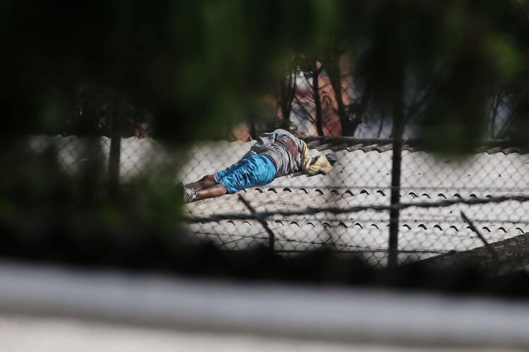 El cuerpo de un hombre se ve en el techo de un edificio dentro de la prisión La Modelo después de un motín de prisioneros que exigían medidas sanitarias del gobierno contra la propagación de la enfermedad coronavirus (COVID-19) en Bogotá, Colombia, el 22 de marzo de 2020