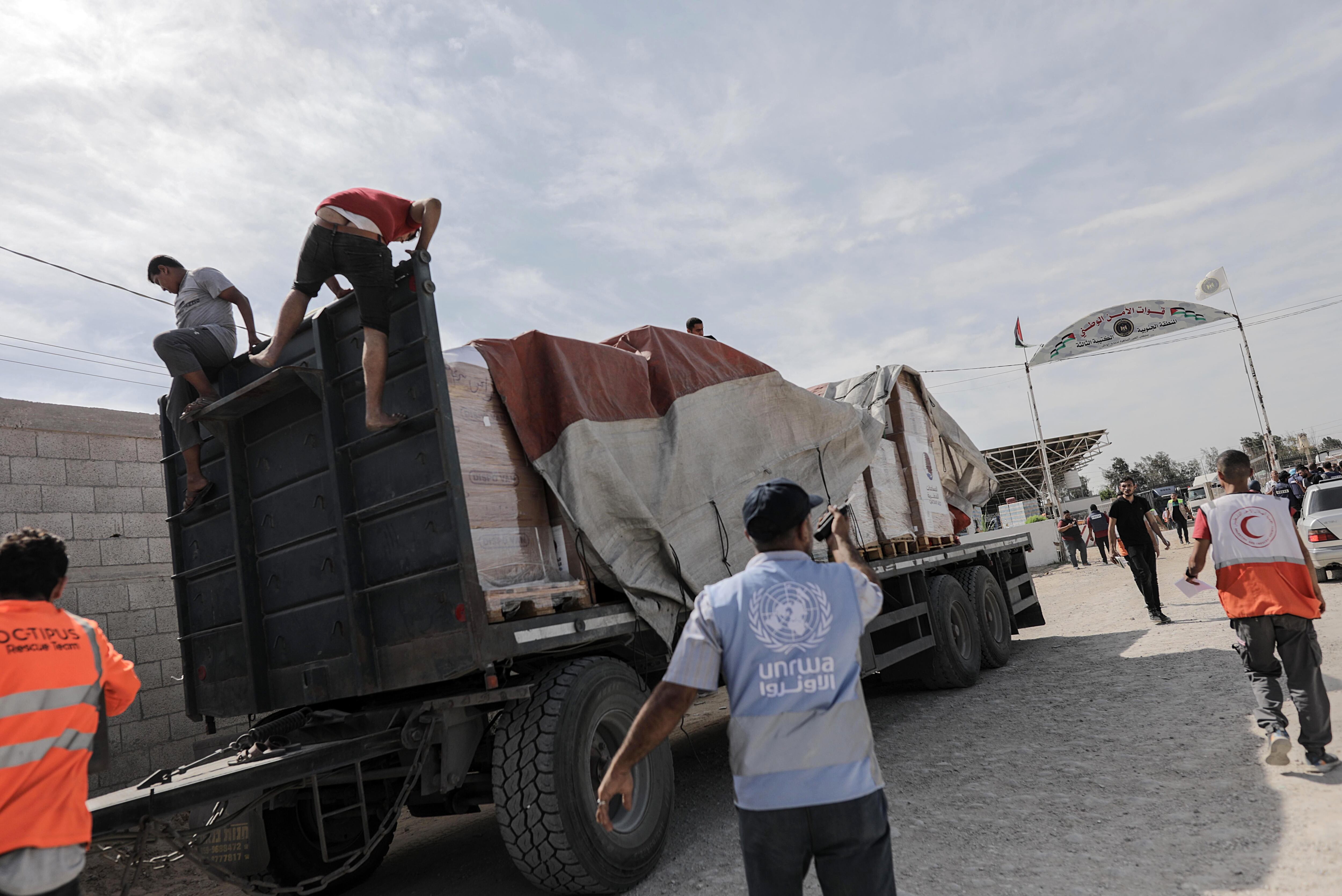 Funcionarios de la Media Luna Roja palestina fueron registrados este sábado, 21 de octubre, al descargar un camión con ayuda humanitaria para la Franja de Gaza, tras su entrada desde Egipto, en Rafah (Palestina). EFE/Haitam Imad

