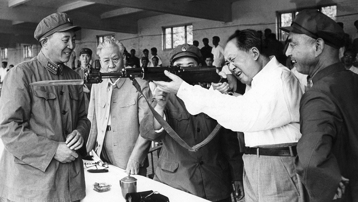 El líder comunista chino y presidente del Partido Comunista (PCCh) Mao Zedong examina un rifle durante su visita a una exposición milita en junio de 1964 (AFP)