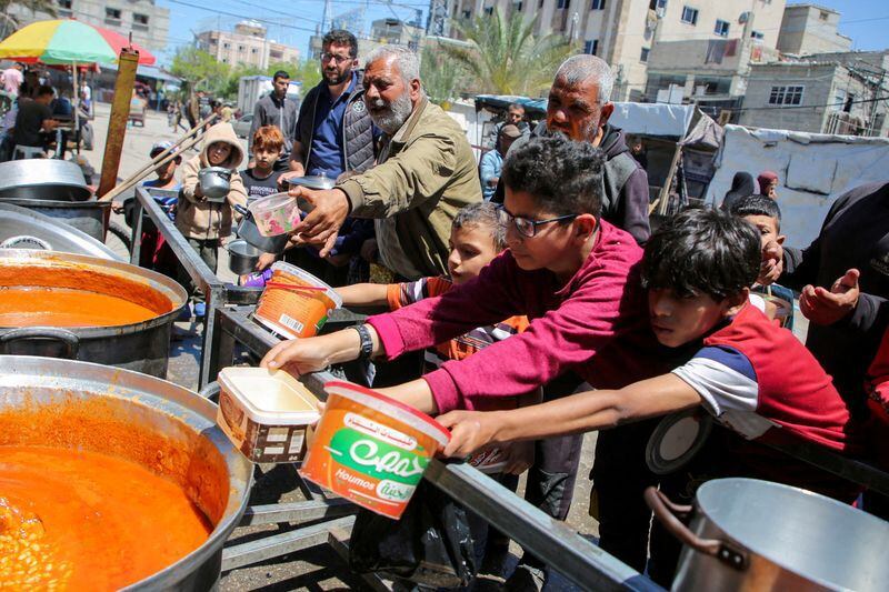 Foto de Archivo: Palestinos se reúnen para recibir alimentos cocinados por una cocina de caridad, en medio de la escasez de suministros de ayuda, después de que las fuerzas israelíes lanzaran una operación terrestre y aérea en la parte oriental de Ráfah, mientras continúa el conflicto en curso entre Israel y Hamás, en Ráfah, en el sur de la Franja de Gaza. 8 de mayo de 2024. REUTERS/Hatem Khaled.