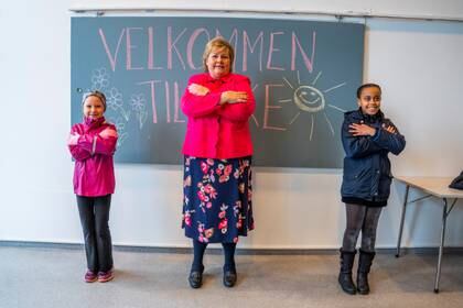 La premier noruega Erna Solberg aprende técnicas de saludo de dos estudiantes durante su visita a la escuela Ellingsrudasen en medio de la cuarentena por el COVID-19 en Oslo, Noruega, el 27 de abril de 2020 (Hakon Mosvold Larsen/NTB Scanpix via REUTERS)