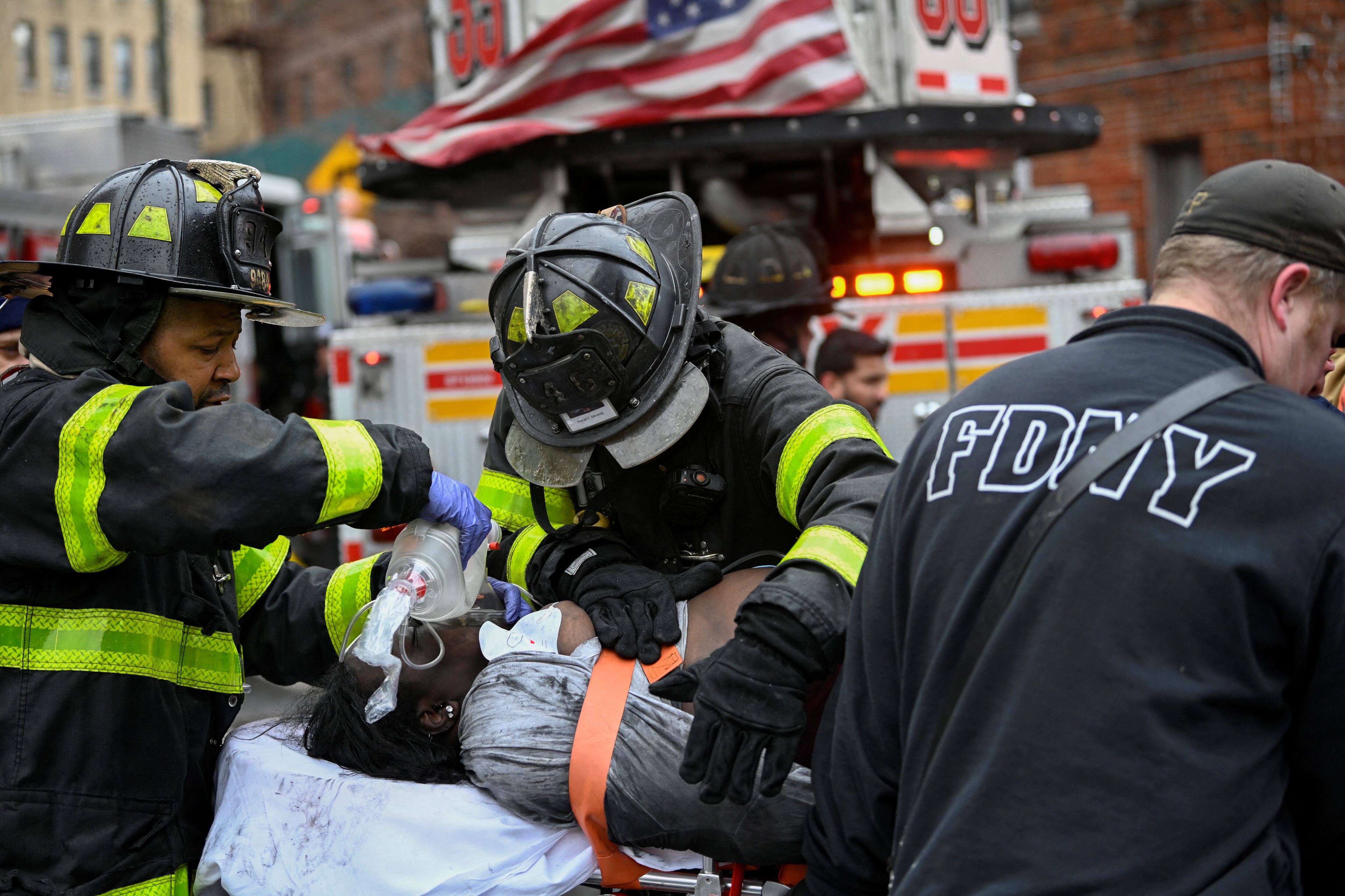 Bomberos asisten a una mujer que resultó herida en el incendio de este domingo en un edificio el Bronx, Nueva York.  REUTERS/Lloyd Mitchell