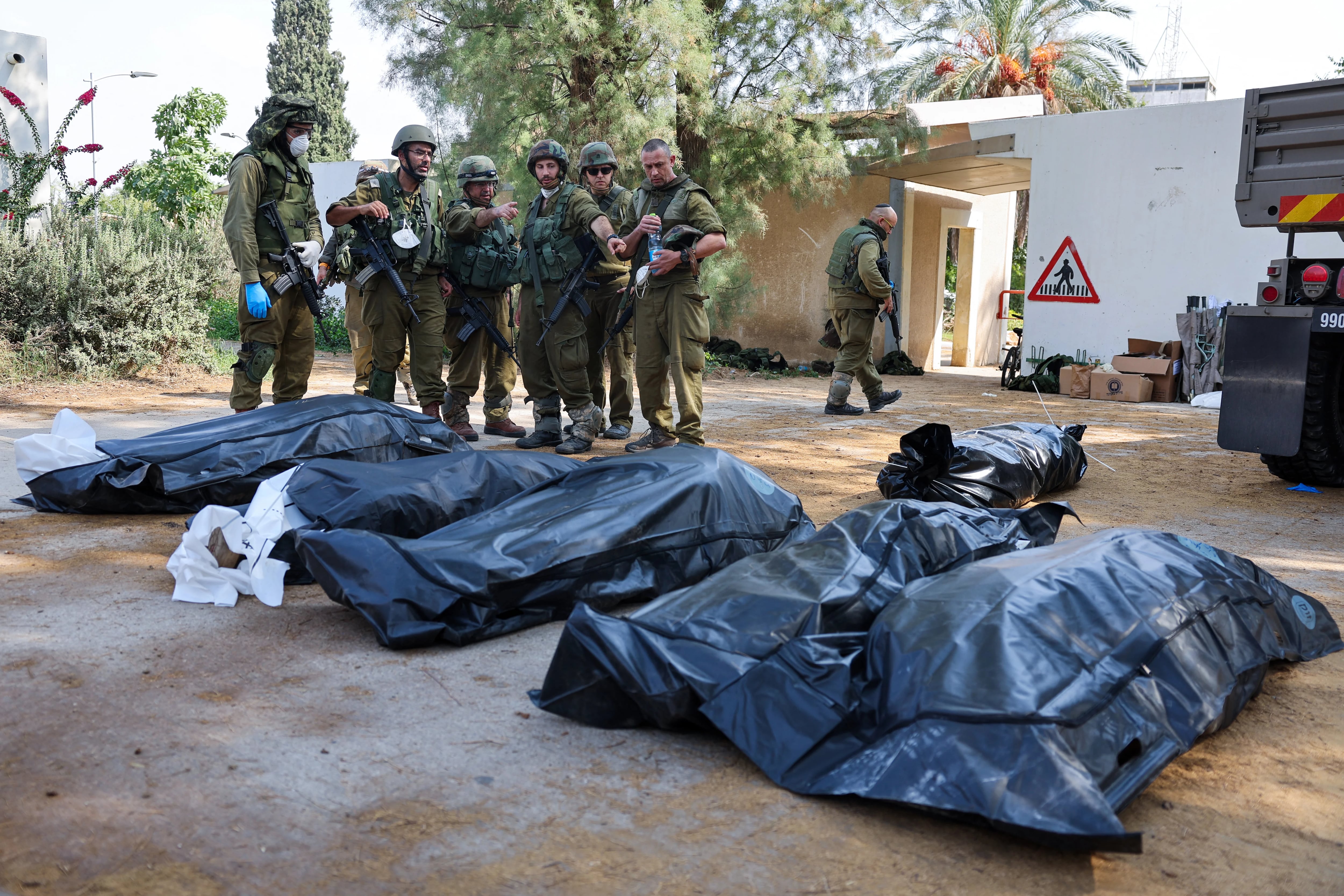 Israeli soldiers prepare to remove the bodies of their compatriots, killed during an attack by the Palestinian militants, in Kfar Aza, south of Israel bordering Gaza Strip, on October 10, 2023. Israel pounded Hamas targets in Gaza on October 10 and said the bodies of 1,500 Islamist militants were found in southern towns recaptured by the army in gruelling battles near the Palestinian enclave. (Photo by JACK GUEZ / AFP)