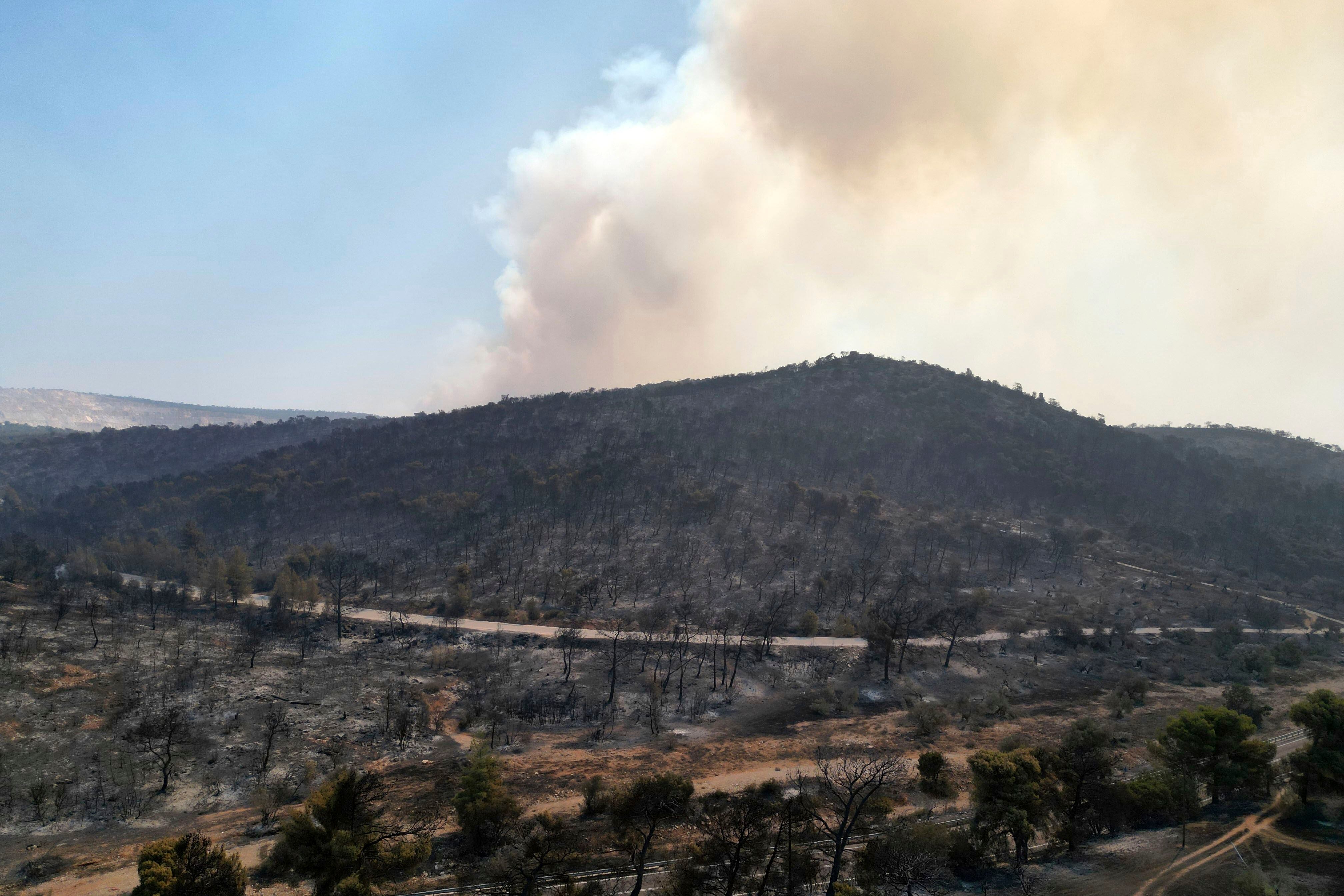 El humo se eleva desde una montaña durante un incendio forestal en Mandra, al oeste de Atenas, Grecia, el miércoles 19 de julio de 2023. Las evacuaciones por incendios forestales han continuado por tercer día en las afueras de la capital griega mientras una segunda ola de calor azota el país mediterráneo desde el oeste tras días de temperaturas récord que han horneado el sur de Europa. (AP/Thanassis Stavrakis)