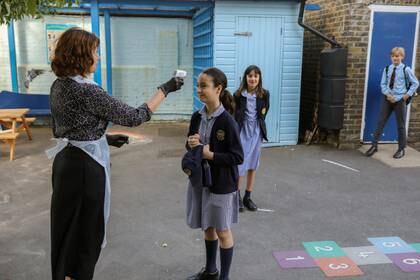 Una alumna de seis años tiene su temperatura controlada por la directora Barbara Wightwick en la Escuela Primaria St John's, mientras algunos niños regresaban a la escuela cuando la cuarentena por la enfermedad coronavirus (COVID-19) se flexibiliza en Fulham, Londres, el 2 de junio de 2020 (REUTERS/Kevin Coombs)