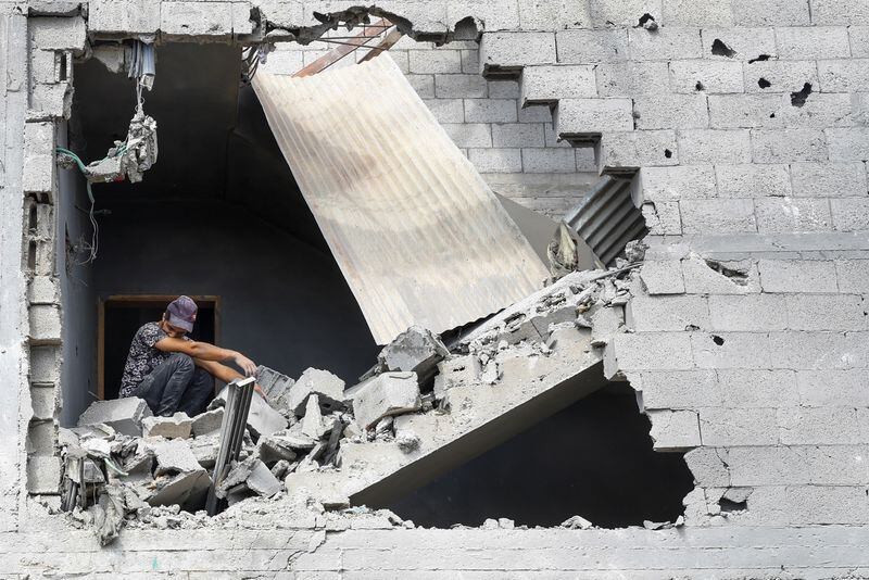 Un hombre sentado entre los escombros mientras palestinos buscan víctimas en una casa destruida por ataques israelíes en Khan Younis, en el sur de la Franja de Gaza. REUTERS/Mohammed Salem